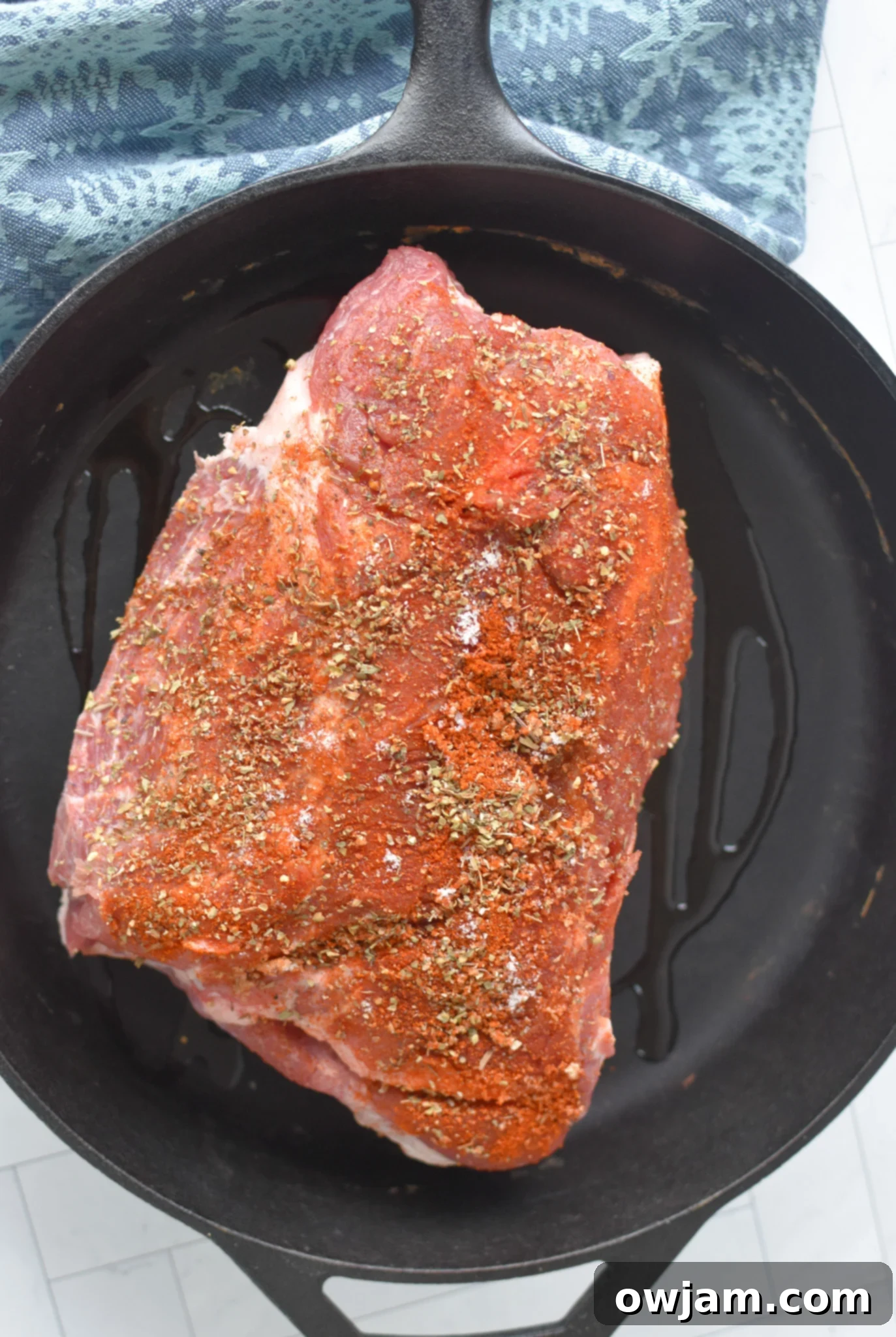 Effortless Oven Pulled Pork Perfection 5 Boston butt searing in a hot cast iron skillet, developing a delicious brown crust before oven roasting.