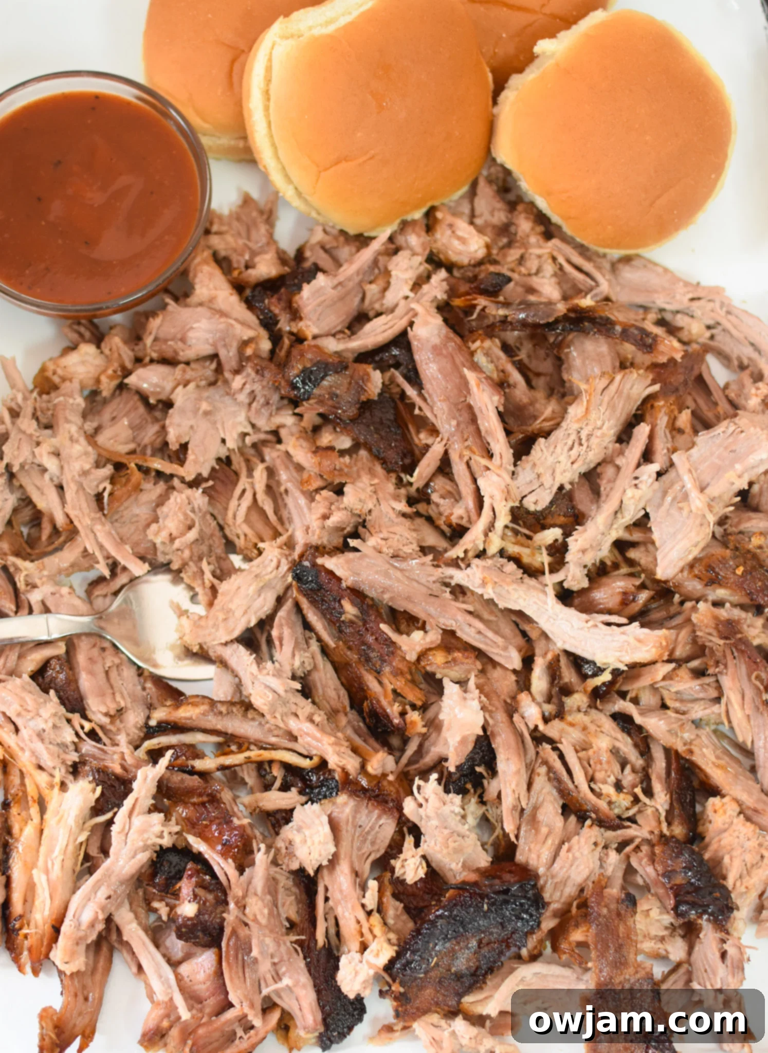 Effortless Oven Pulled Pork Perfection 7 Juicy shredded pork Boston butt piled high on buns with barbecue sauce, ready to be enjoyed as sandwiches.