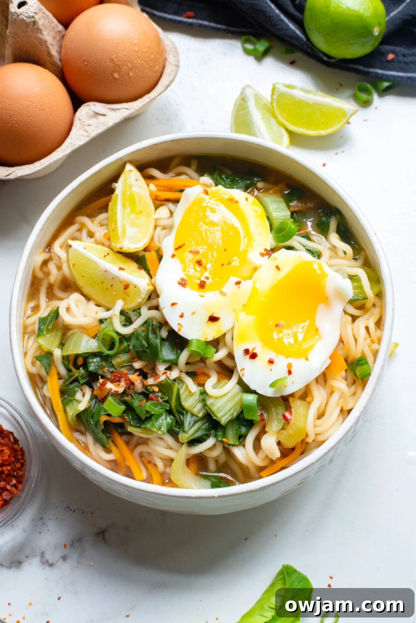 Easy Ramen Noodle Soup in a white bowl, garnished with green onions, chili flakes, and a lime wedge.