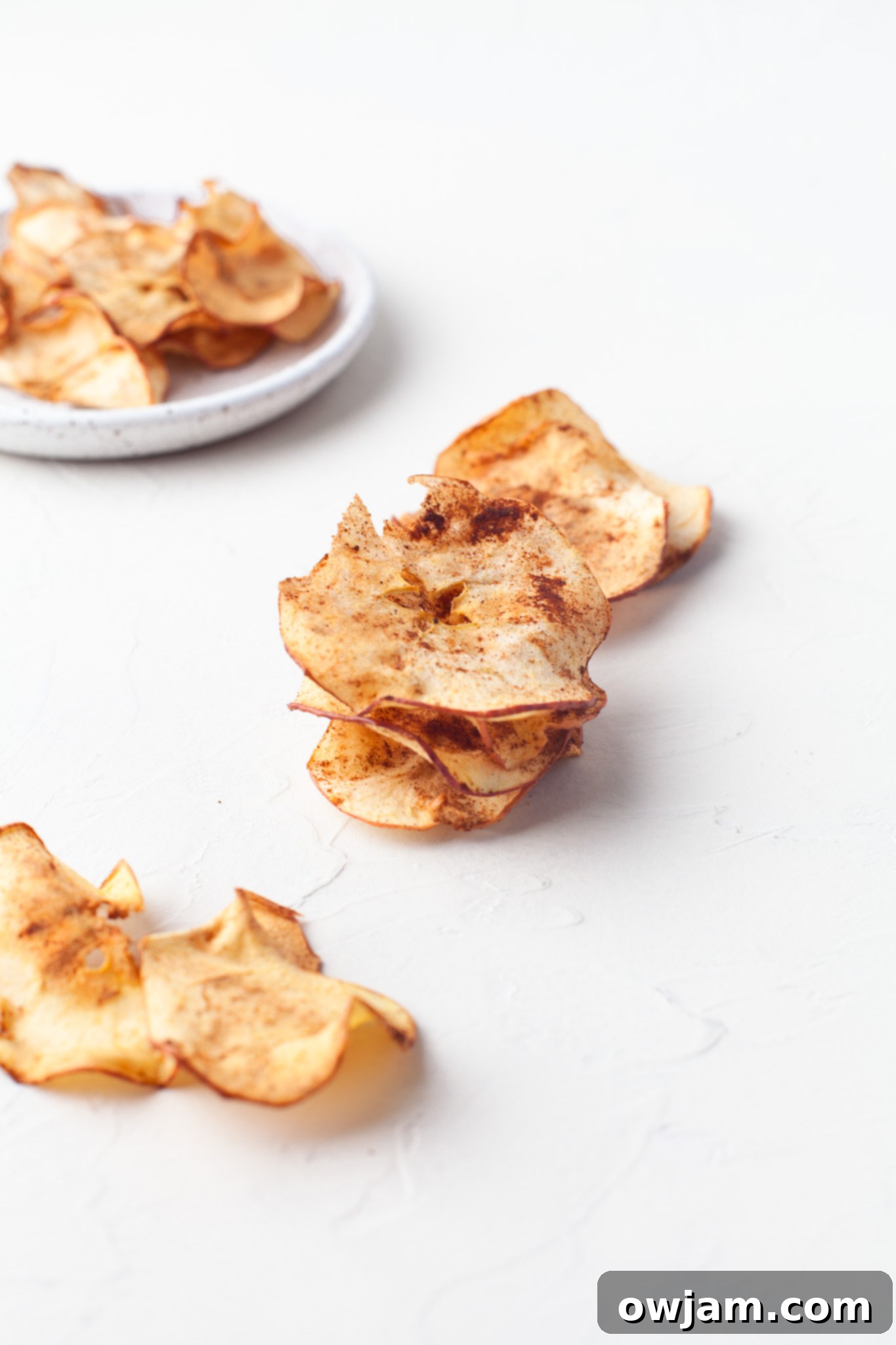Perfectly Crispy Air Fryer Apple Slices 9 Easy Air Fryer Apple Chips displayed on a white table, highlighting their inviting, golden-brown texture.