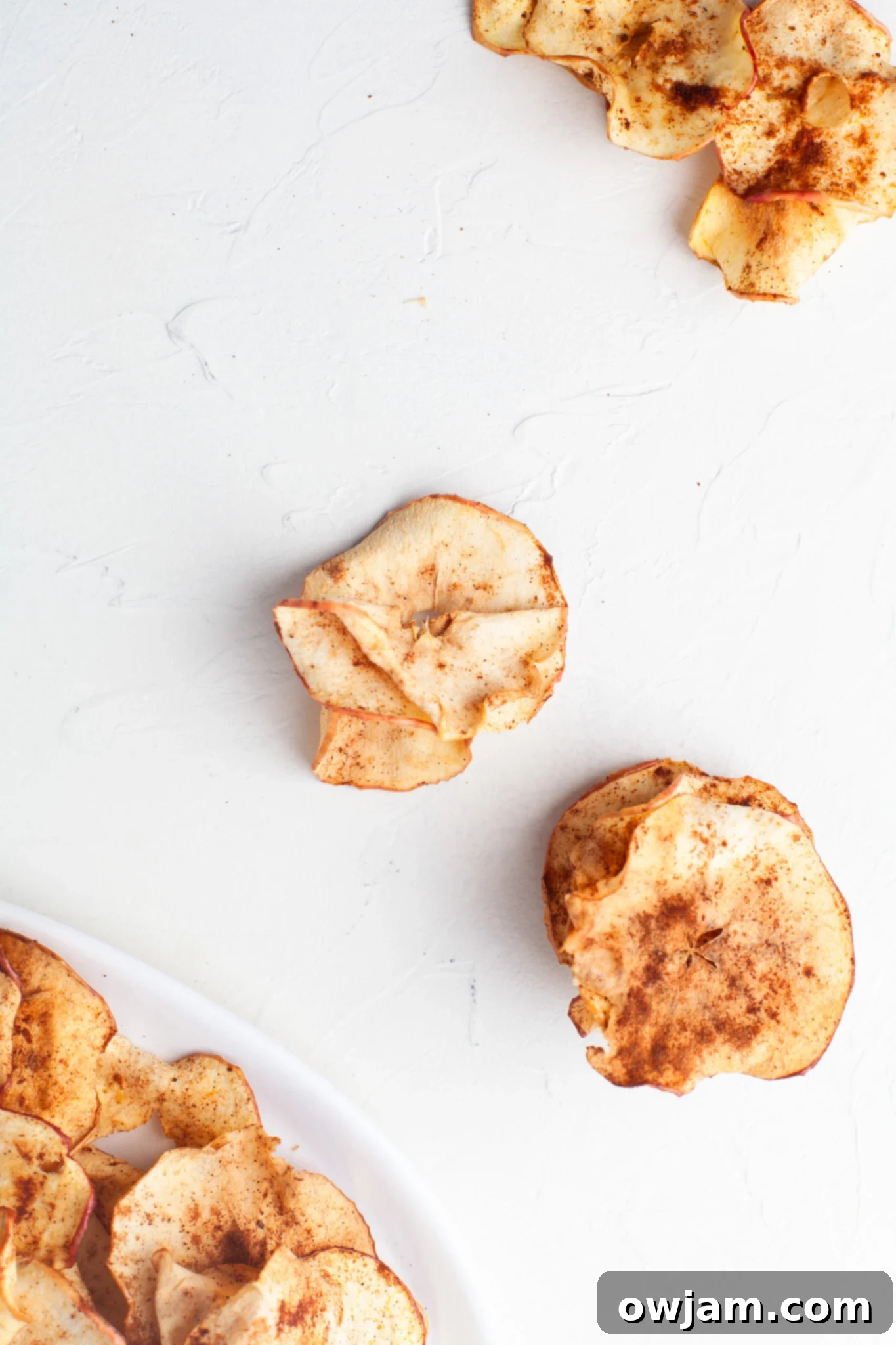 Perfectly Crispy Air Fryer Apple Slices 10 Easy Air Fryer Apple Chips artfully arranged on a white table, ready to be enjoyed.