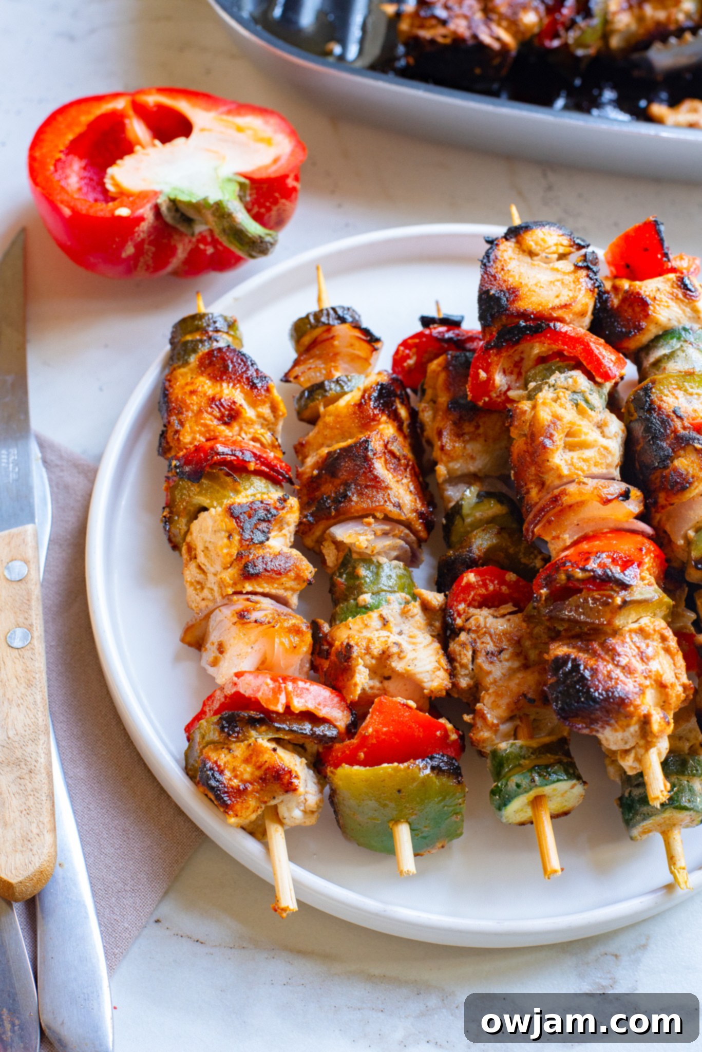 Zesty Greek Chicken Kabobs 2 Greek Marinated Chicken Kabobs with Lemon on a white plate, garnished with fresh herbs.