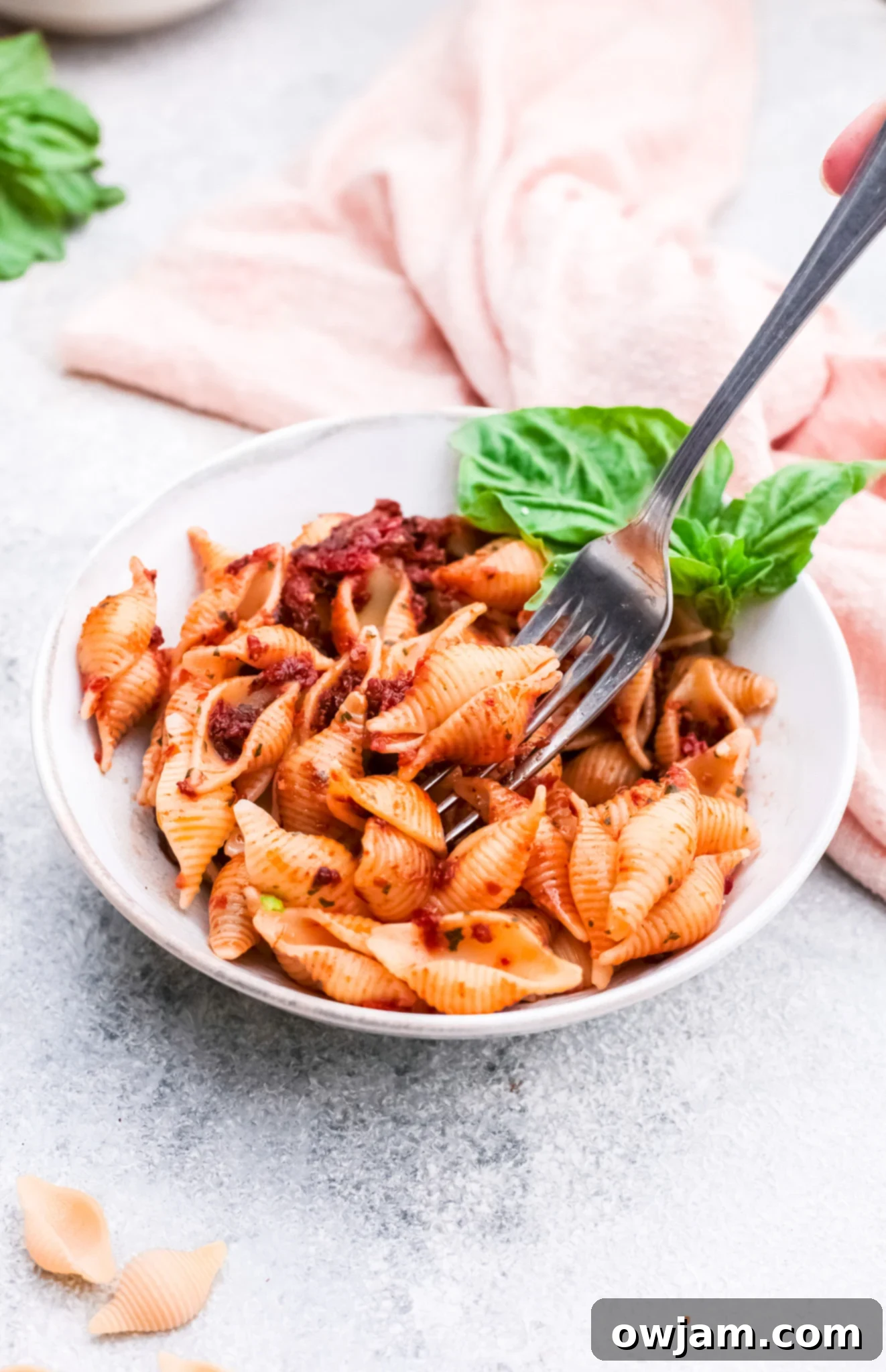 A bowl of creamy Sun-Dried Tomato Pesto Pasta, ready to be enjoyed, with a fork digging into the rich sauce and perfectly cooked pasta.