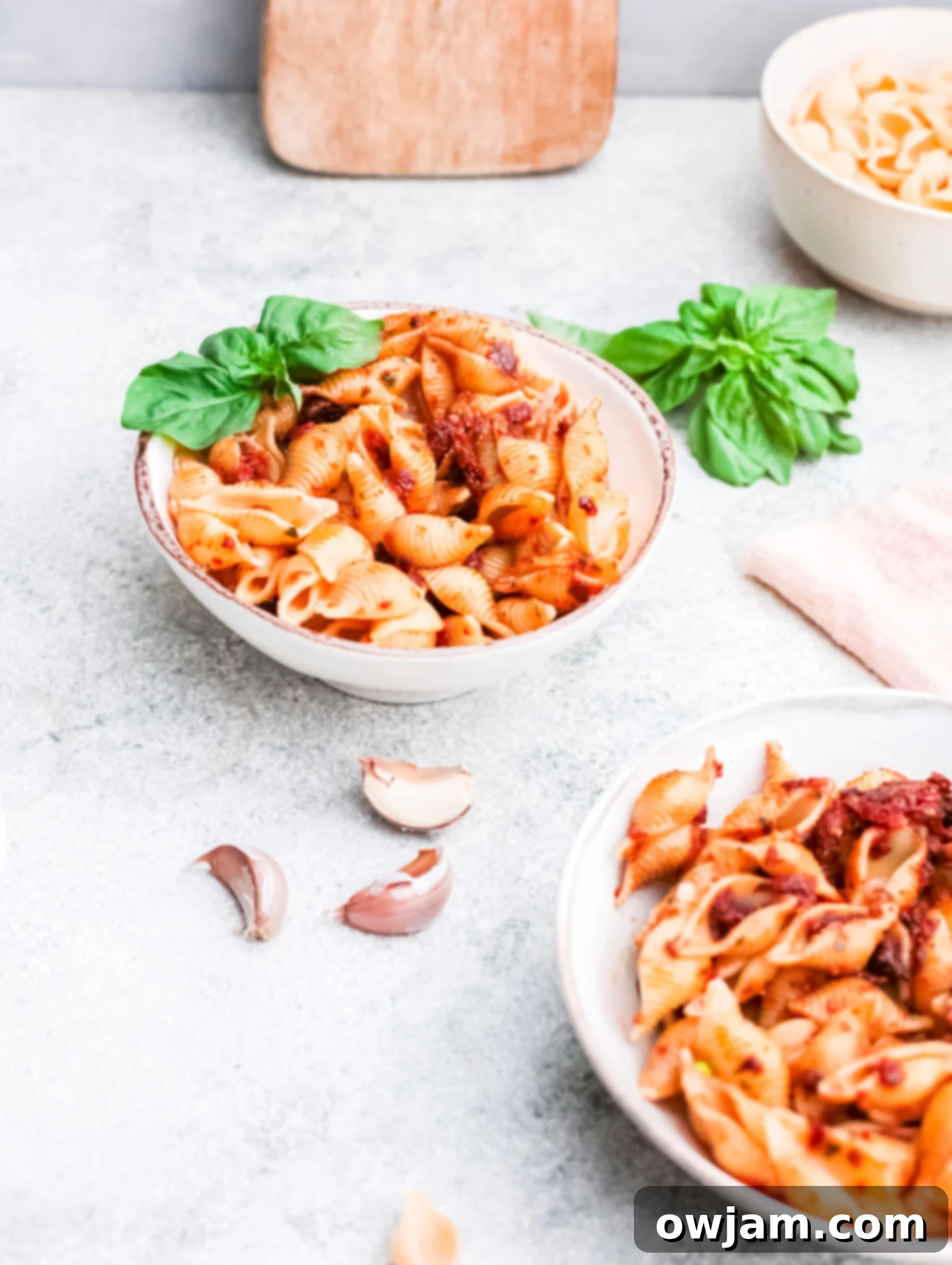 A close-up of Sun-Dried Tomato Pesto Pasta in a bowl, with a neatly folded napkin in the background, suggesting a prepared meal setting.