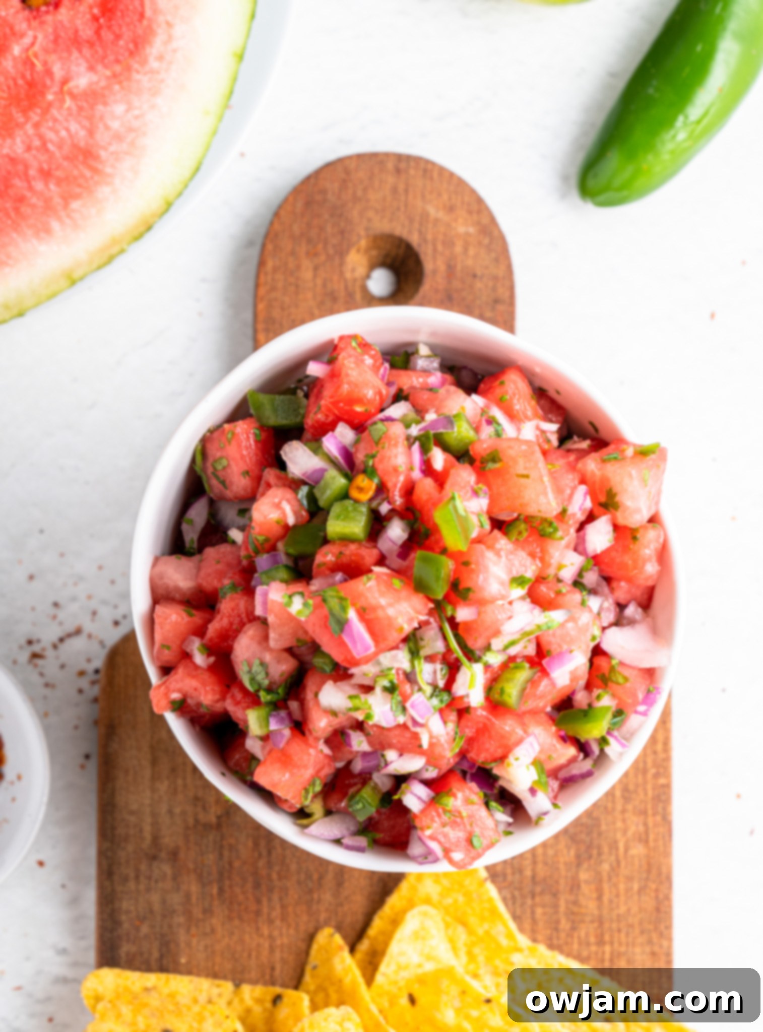 Effortless Watermelon Salsa 5 Easy Watermelon Salsa ingredients being chopped on a wooden cutting board, with fresh cilantro and lime nearby.