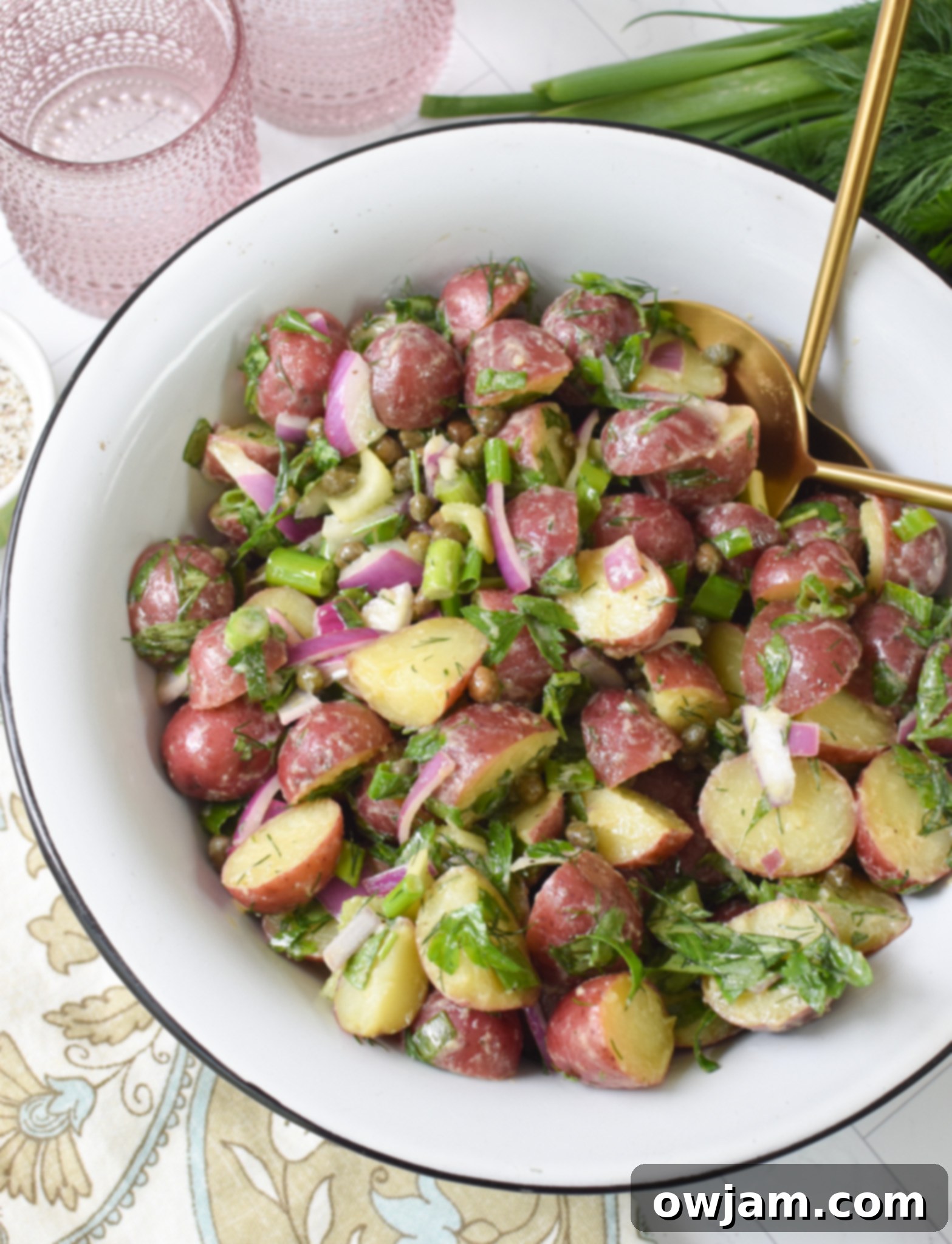 No Mayo Potato Salad in a white bowl with gold spoons, highlighting its fresh and light appeal.