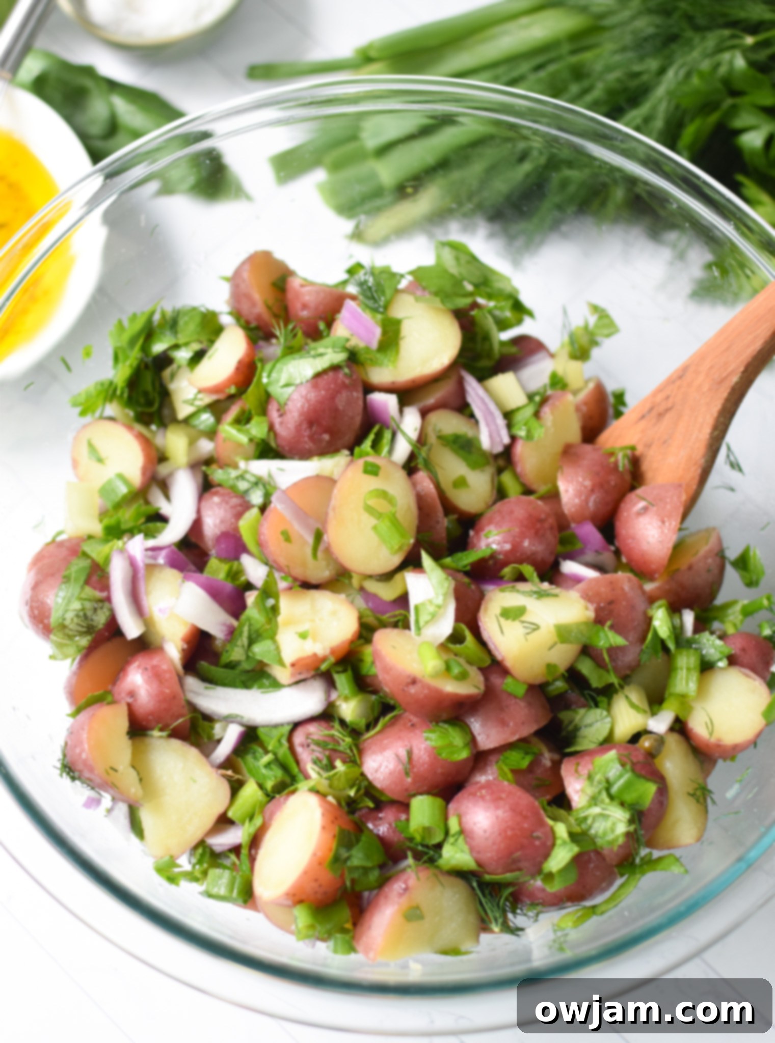 The finished No Mayo Potato Salad in a clear bowl, showing the vibrant dressing.