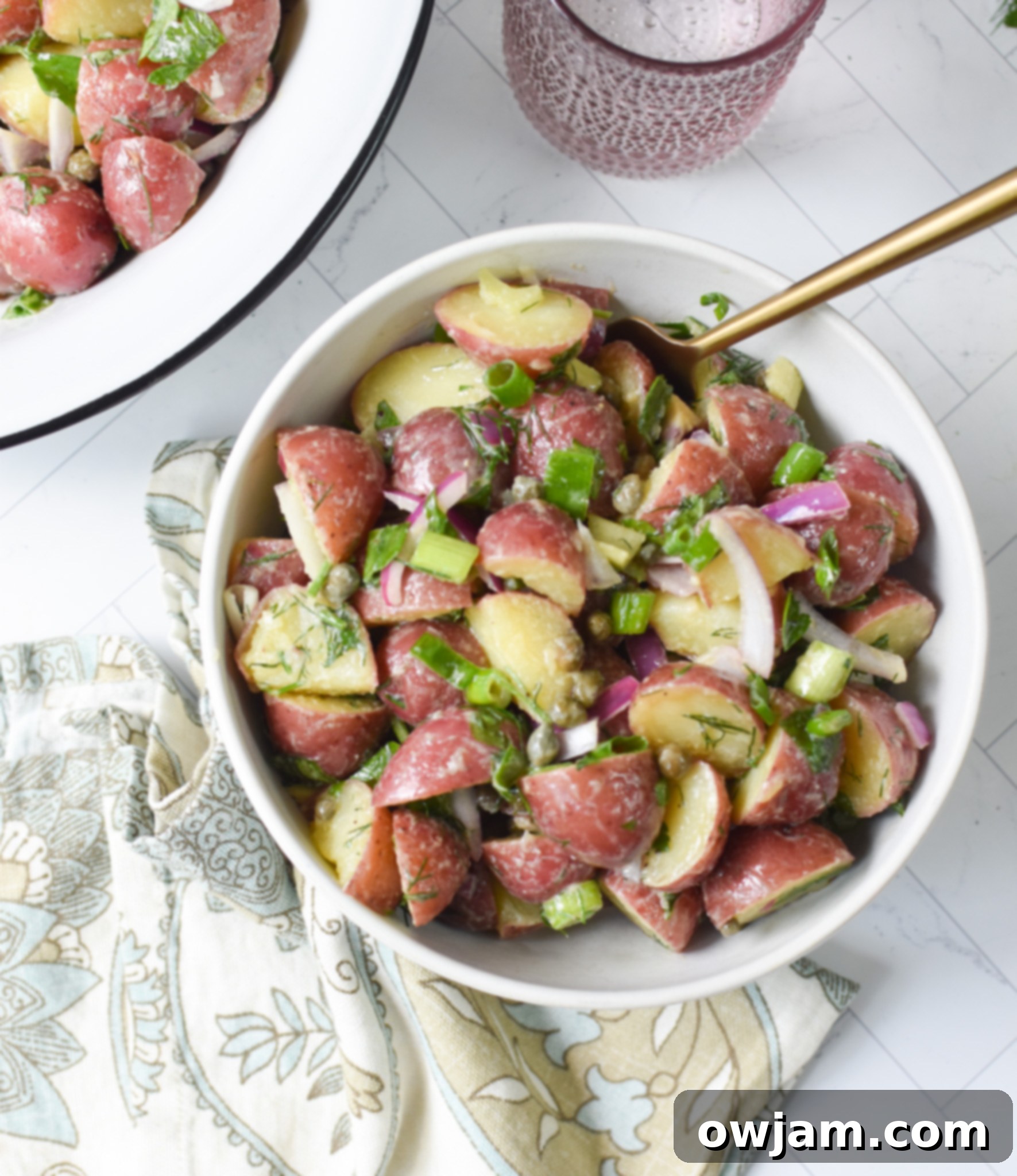 No Mayo Potato Salad in a small white bowl, showing off its colorful ingredients.