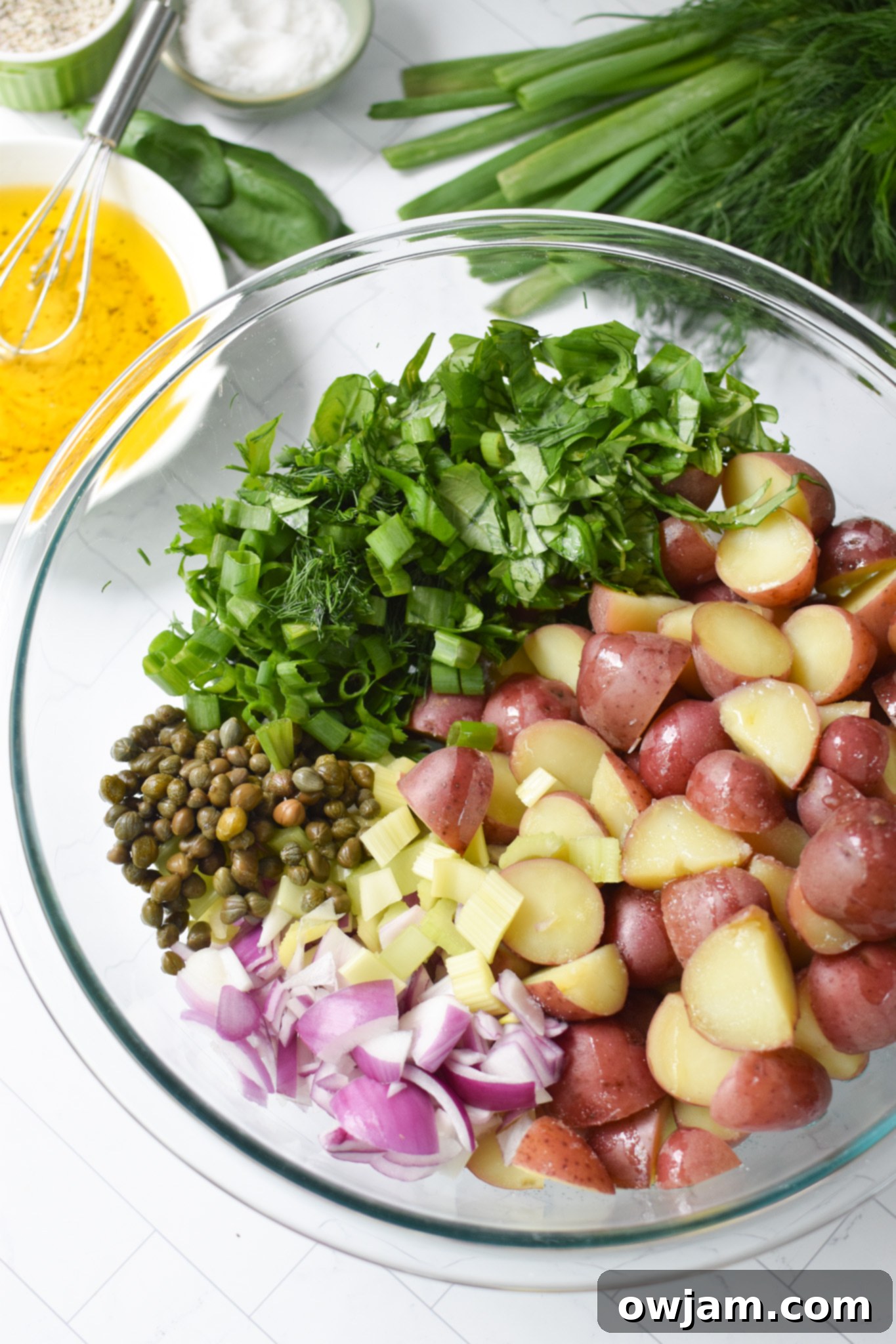 Mixed vegetables and potatoes in a clear bowl for No Mayo Potato Salad.