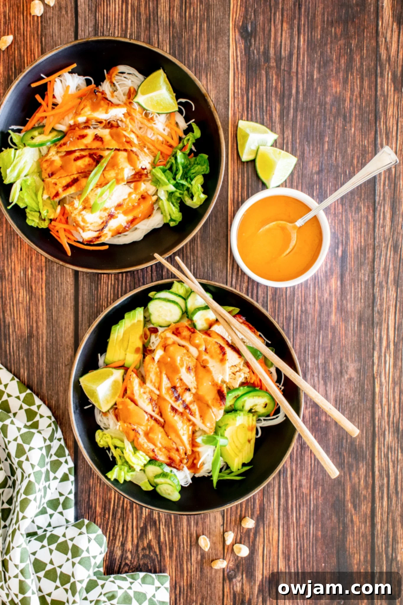 Thai Chicken Noodle Salad with sauce. A bowl of Thai chicken noodle salad being drizzled with peanut sauce.