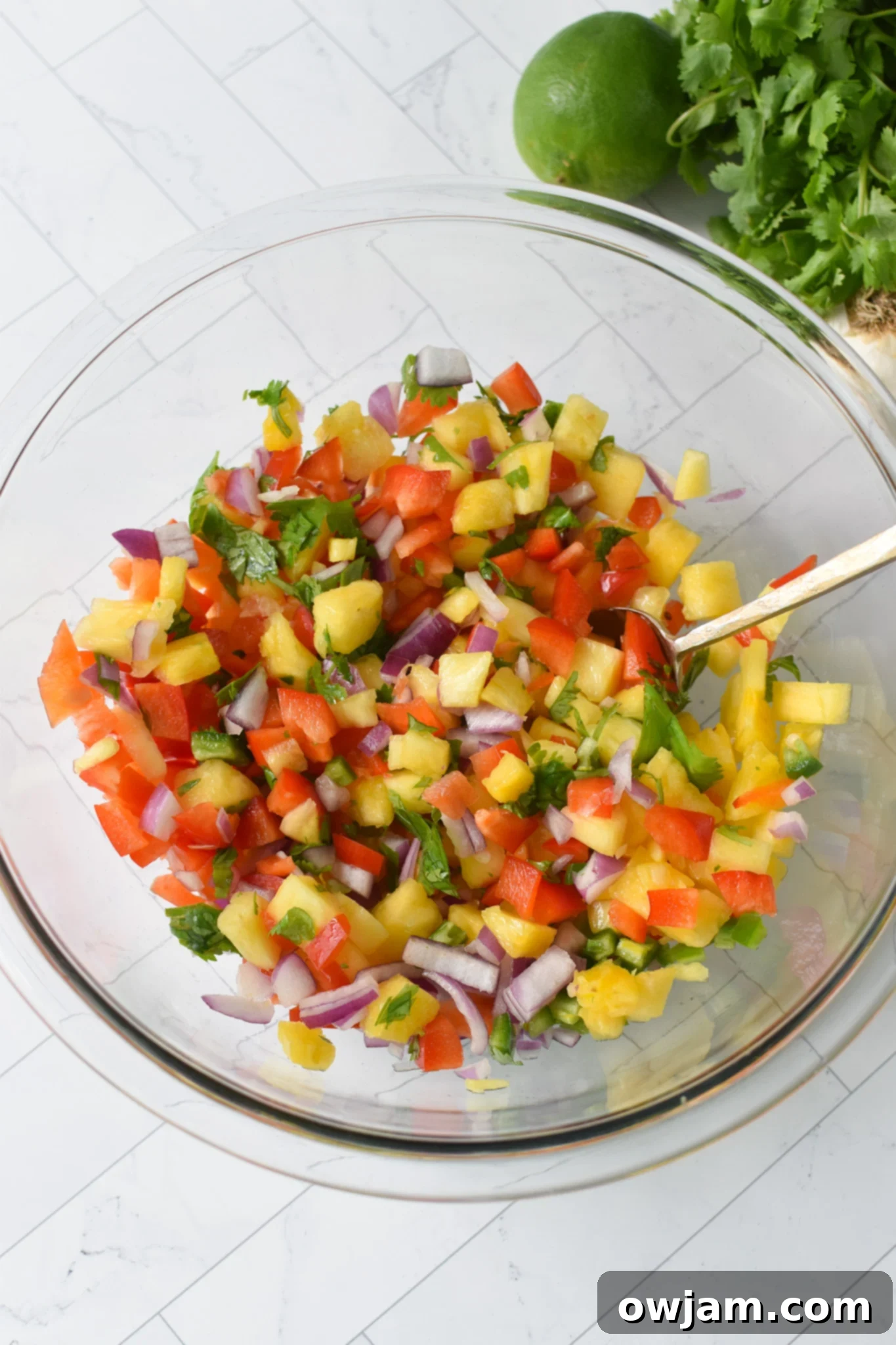 Balsamic Marinated Skirt Steak pineapple salsa in a clear bowl with a spoon. 