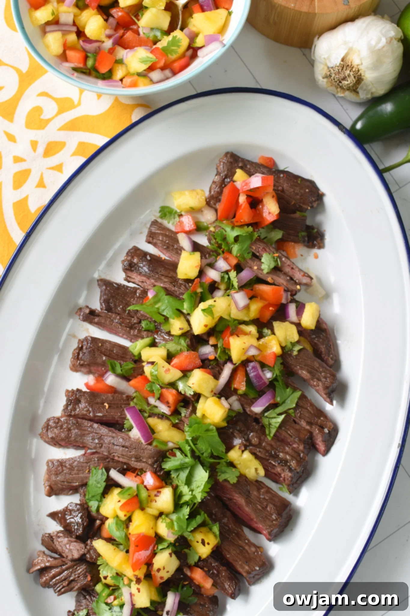 Balsamic Marinated Skirt Steak steak on a white platter with a blue rim. 