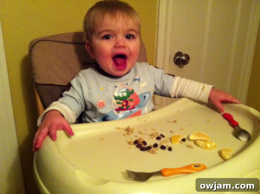 A toddler happily eating at a dining table, showcasing a positive mealtime experience despite potential mess.