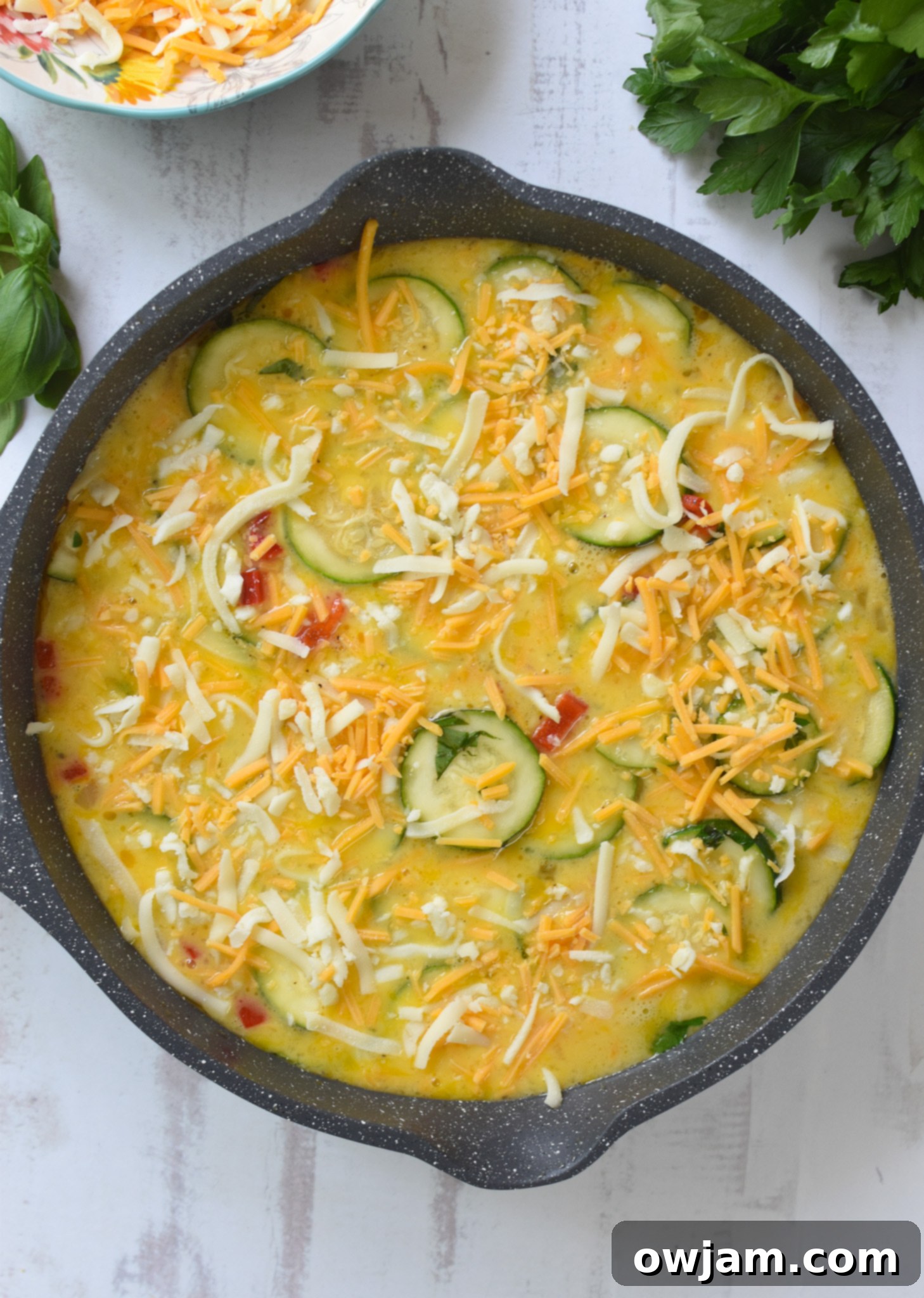 Savory Zucchini Frittata 11 Zucchini Frittata Recipe with cheese sprinkled on top, ready for the oven.