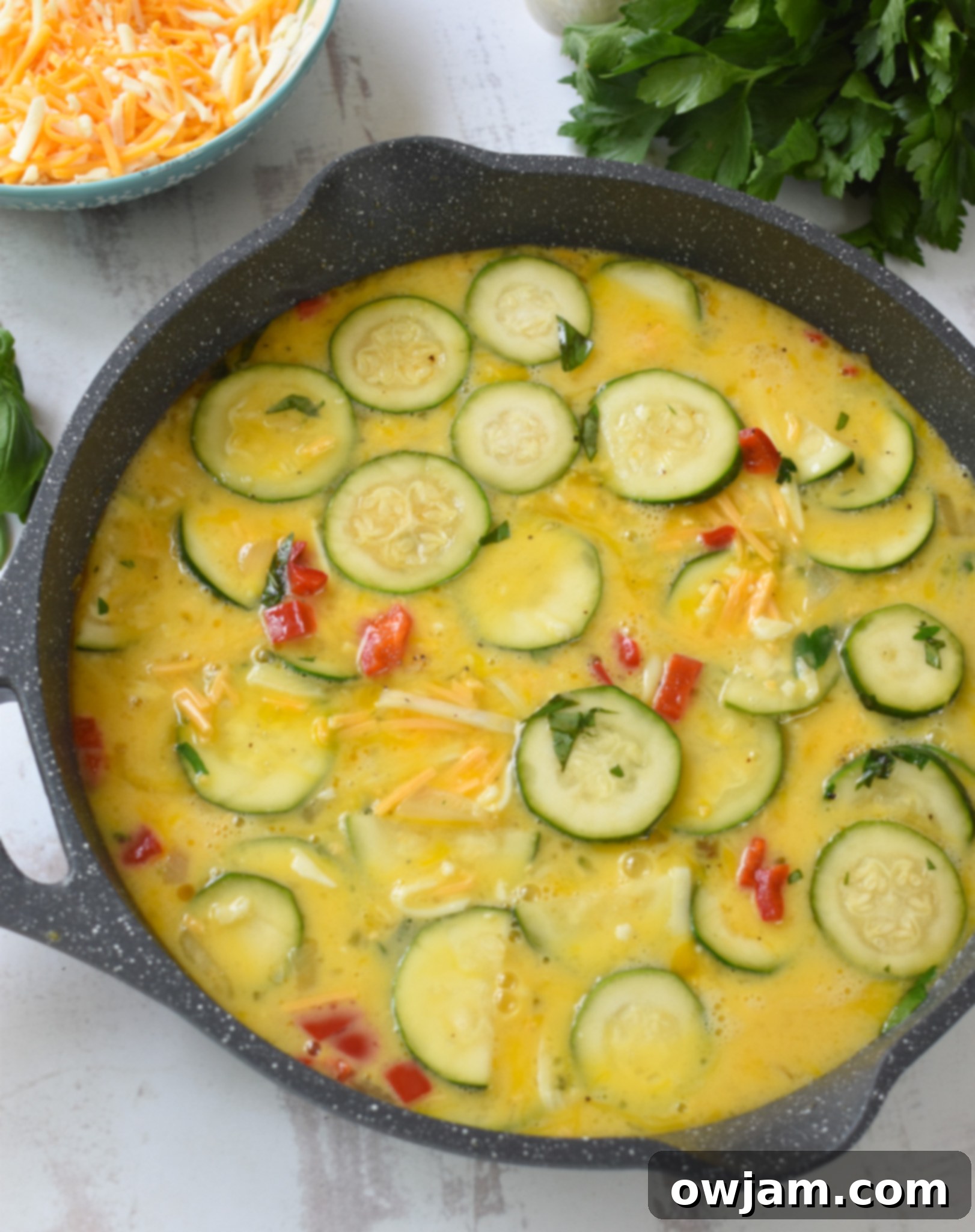 Savory Zucchini Frittata 10 Eggs and sautéed vegetables combined in a skillet, ready for baking.