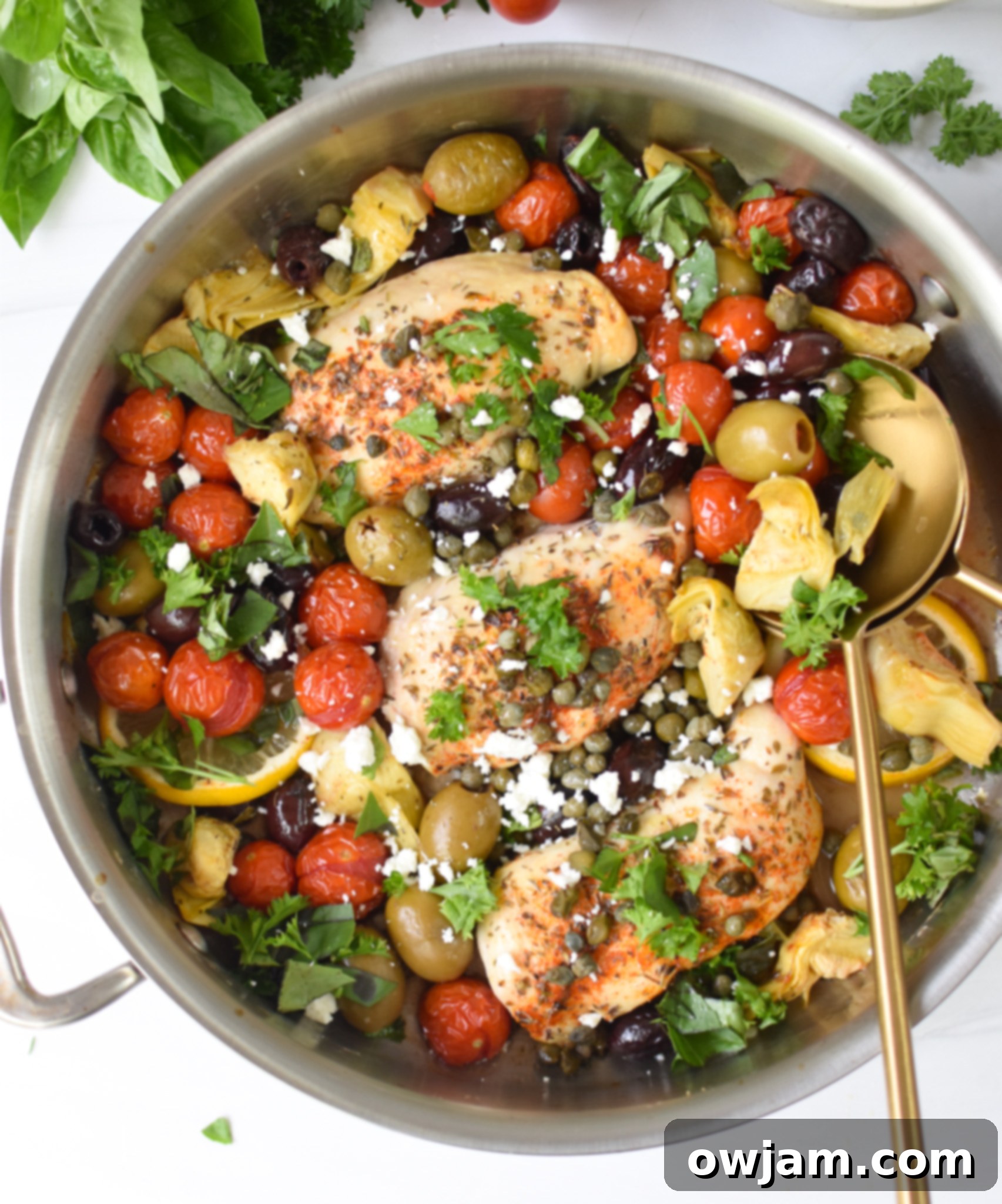 Easy Mediterranean Chicken Skillet 2 Mediterranean Skillet Chicken in a cast iron skillet with a fork and spoon, ready to be served.
