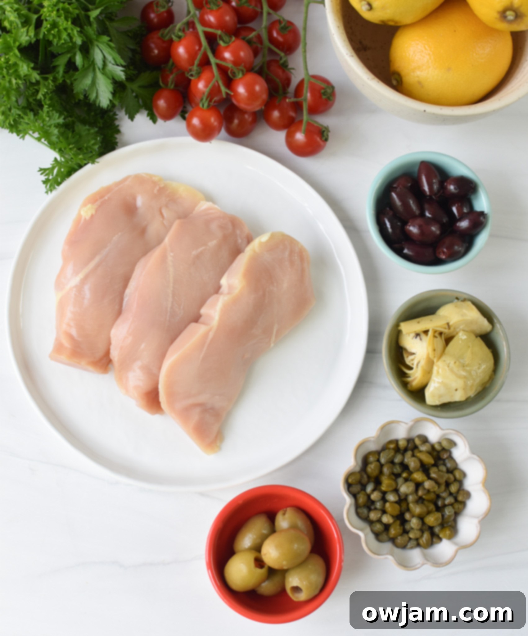 Easy Mediterranean Chicken Skillet 4 Ingredients laid out for Mediterranean Skillet Chicken, including chicken, olives, tomatoes, lemon, and spices.