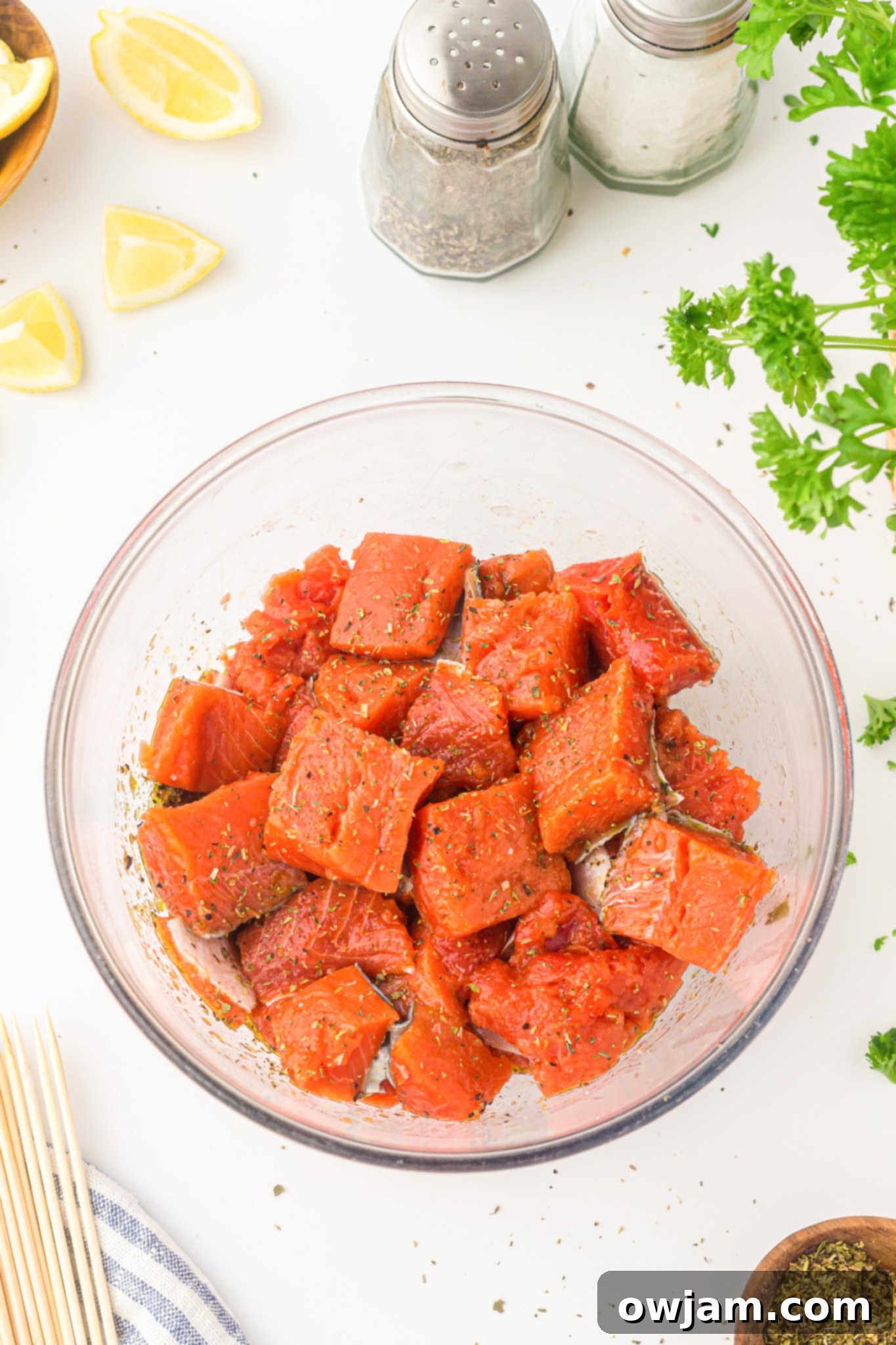 Zesty Lemon Salmon Skewers 7 Easy Lemon Salmon Kabobs: salmon cubes marinating in a bowl with lemon slices.