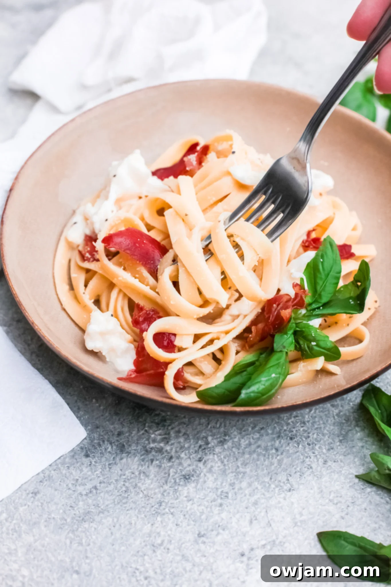 Prosciutto Pasta served in a bowl with burrata and fresh basil.