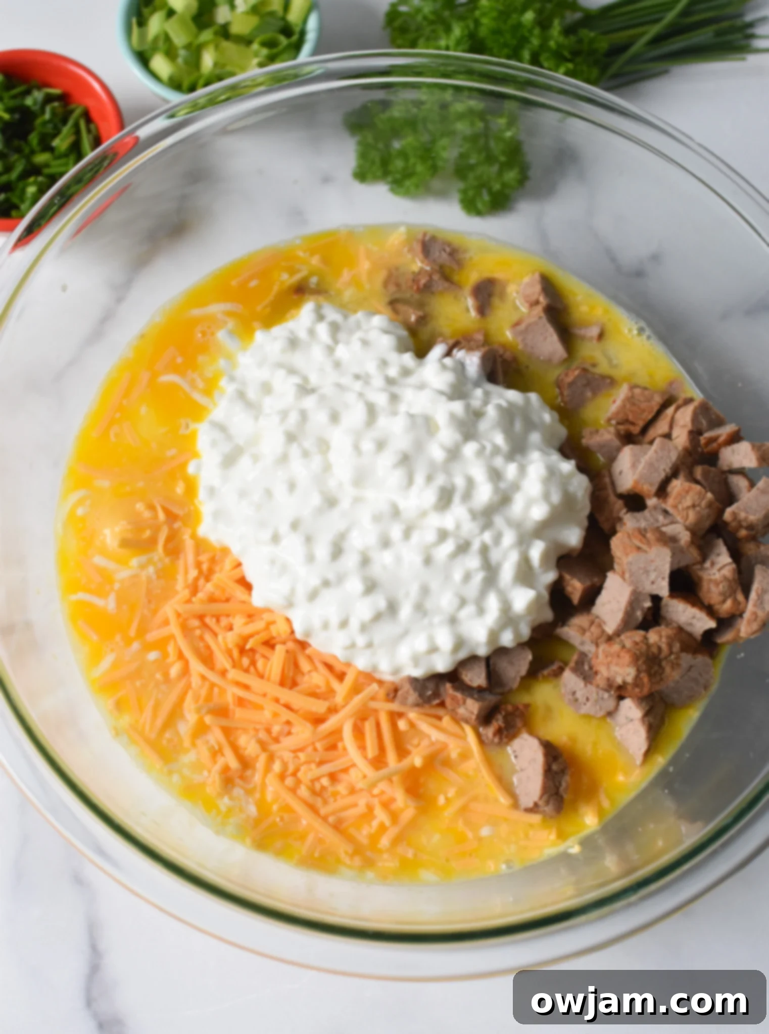 All ingredients for Cheese and Sausage Baked Eggs gathered in a large mixing bowl before stirring.