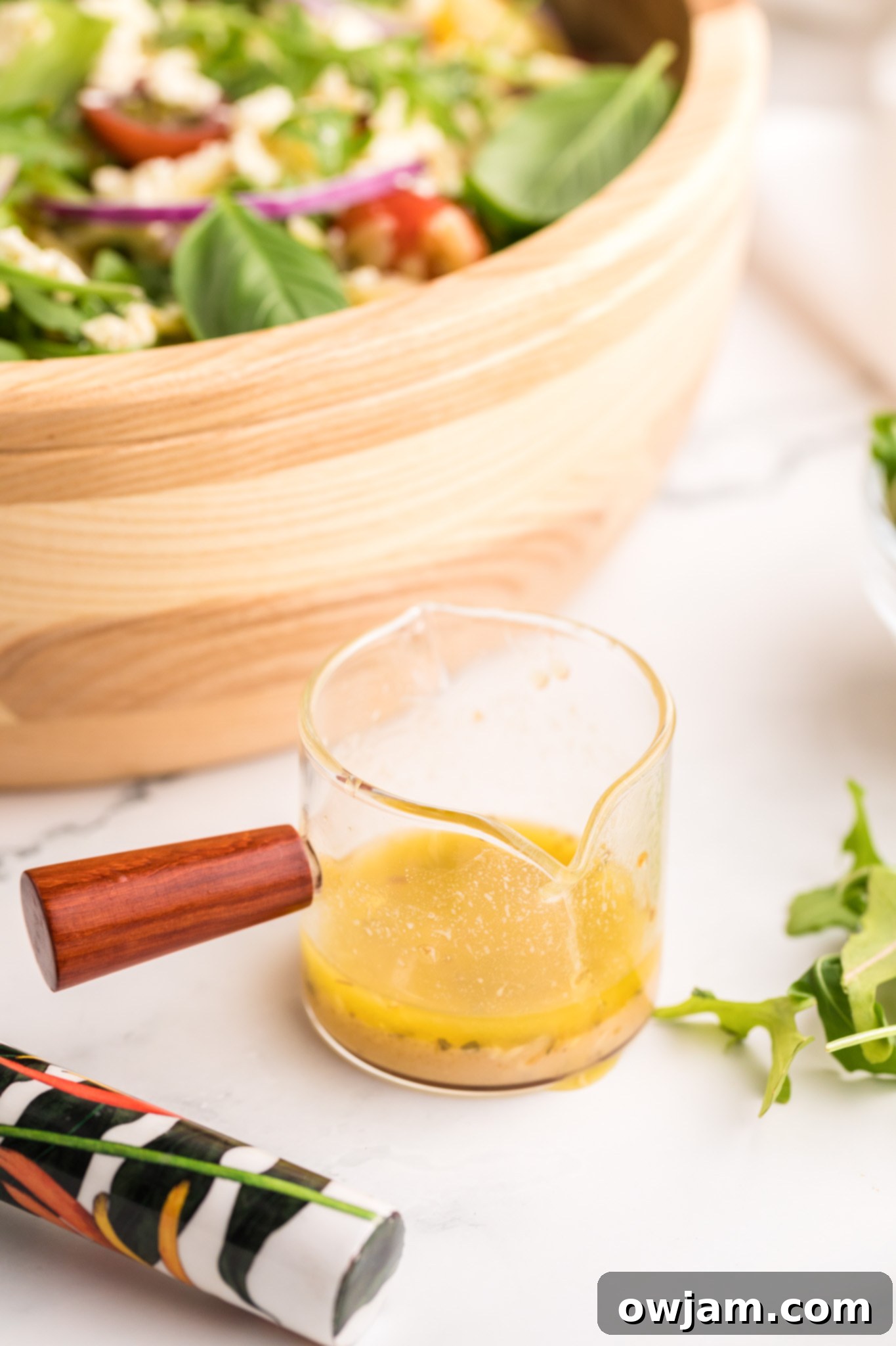 A small jar filled with homemade Greek-style salad dressing, ready to be poured.