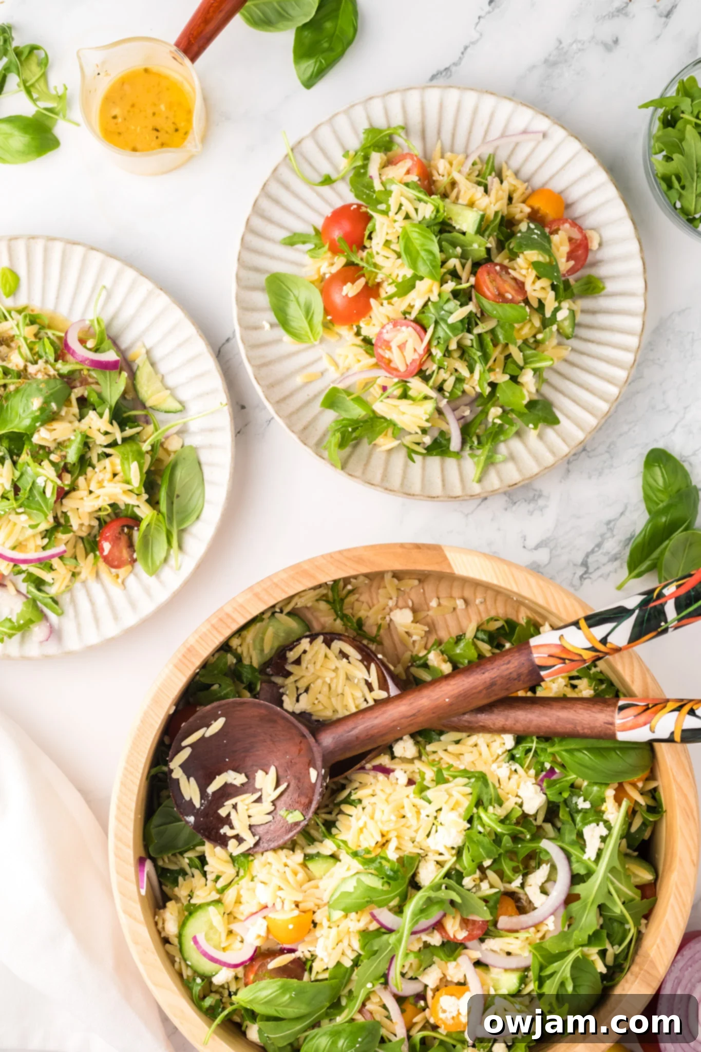Two plates of Arugula Orzo Salad arranged on a table, ready for serving.