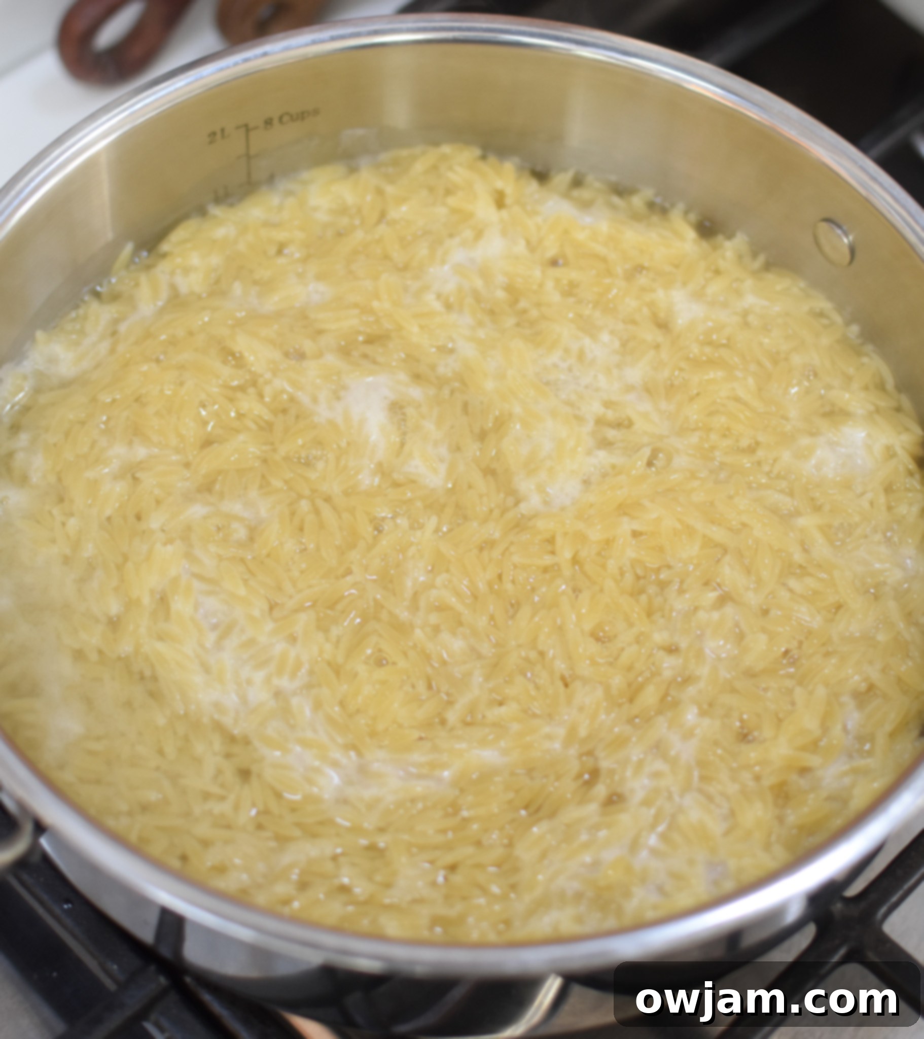 Orzo pasta cooking in a pot, absorbing liquid, a key step in preparing Lemon Chicken Orzo.