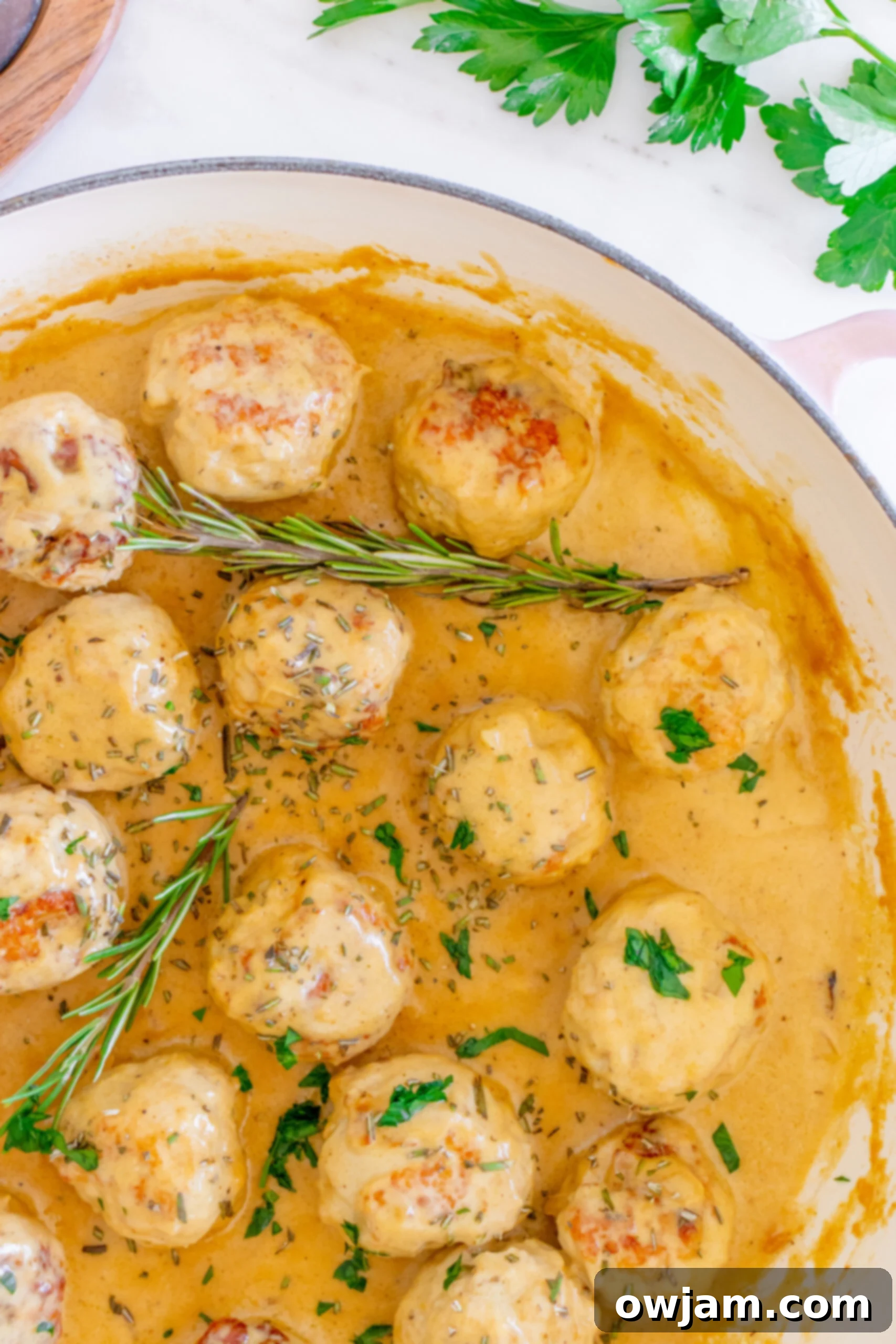 Sweet & Savory Maple Dijon Turkey Meatballs 6 A dish of Maple Dijon Turkey Meatballs garnished with fresh rosemary leaves.