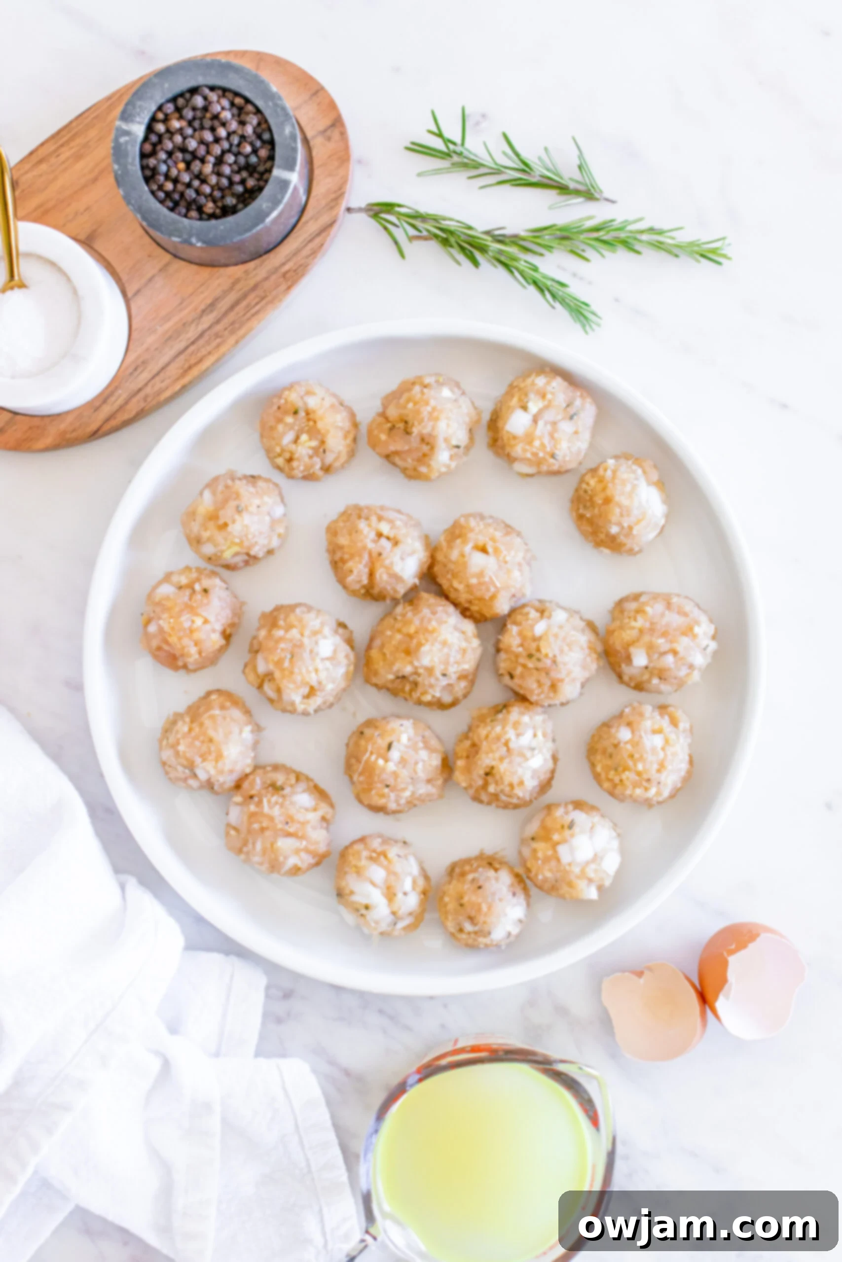 Sweet & Savory Maple Dijon Turkey Meatballs 8 Uncooked Maple Dijon Turkey Meatballs neatly arranged on a plate.