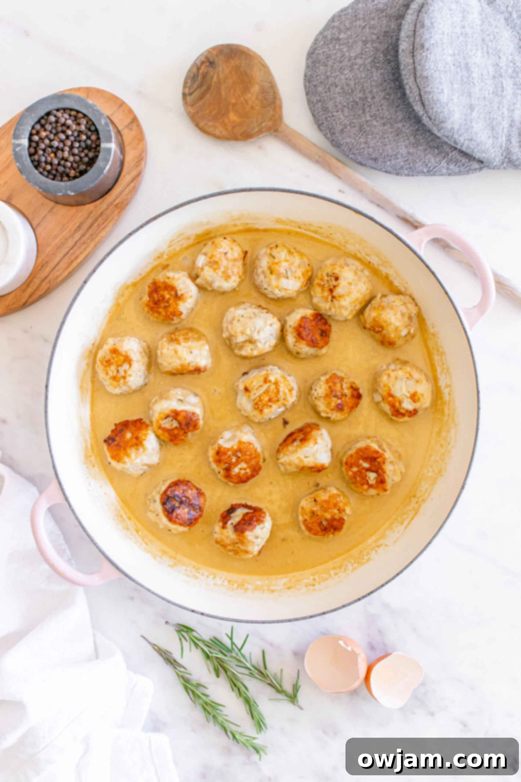 Sweet & Savory Maple Dijon Turkey Meatballs 10 Maple Dijon Turkey Meatballs being added to the creamy sauce in a Dutch oven.