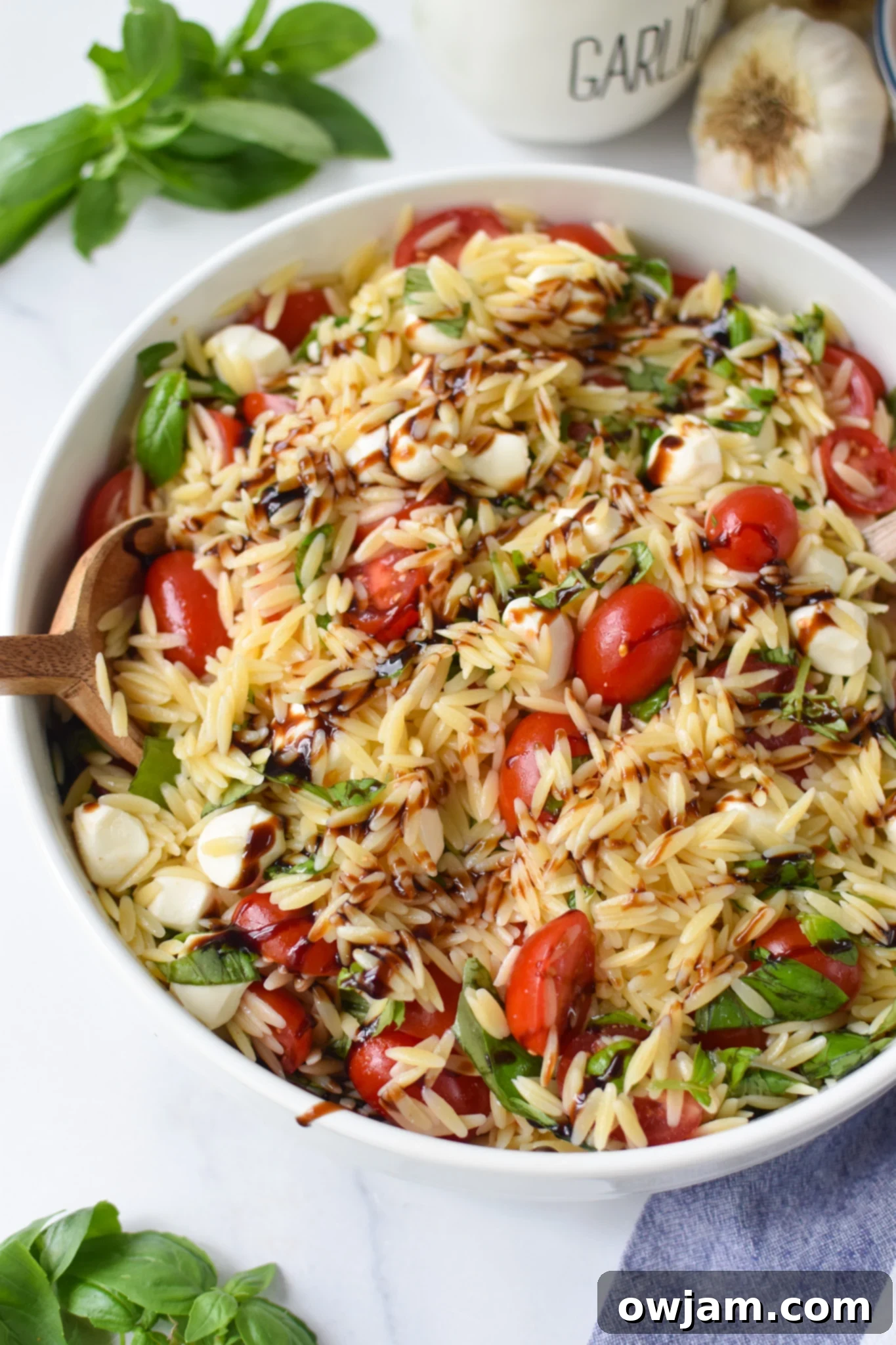 Caprese Orzo Pasta Salad with balsamic in a large bowl. 