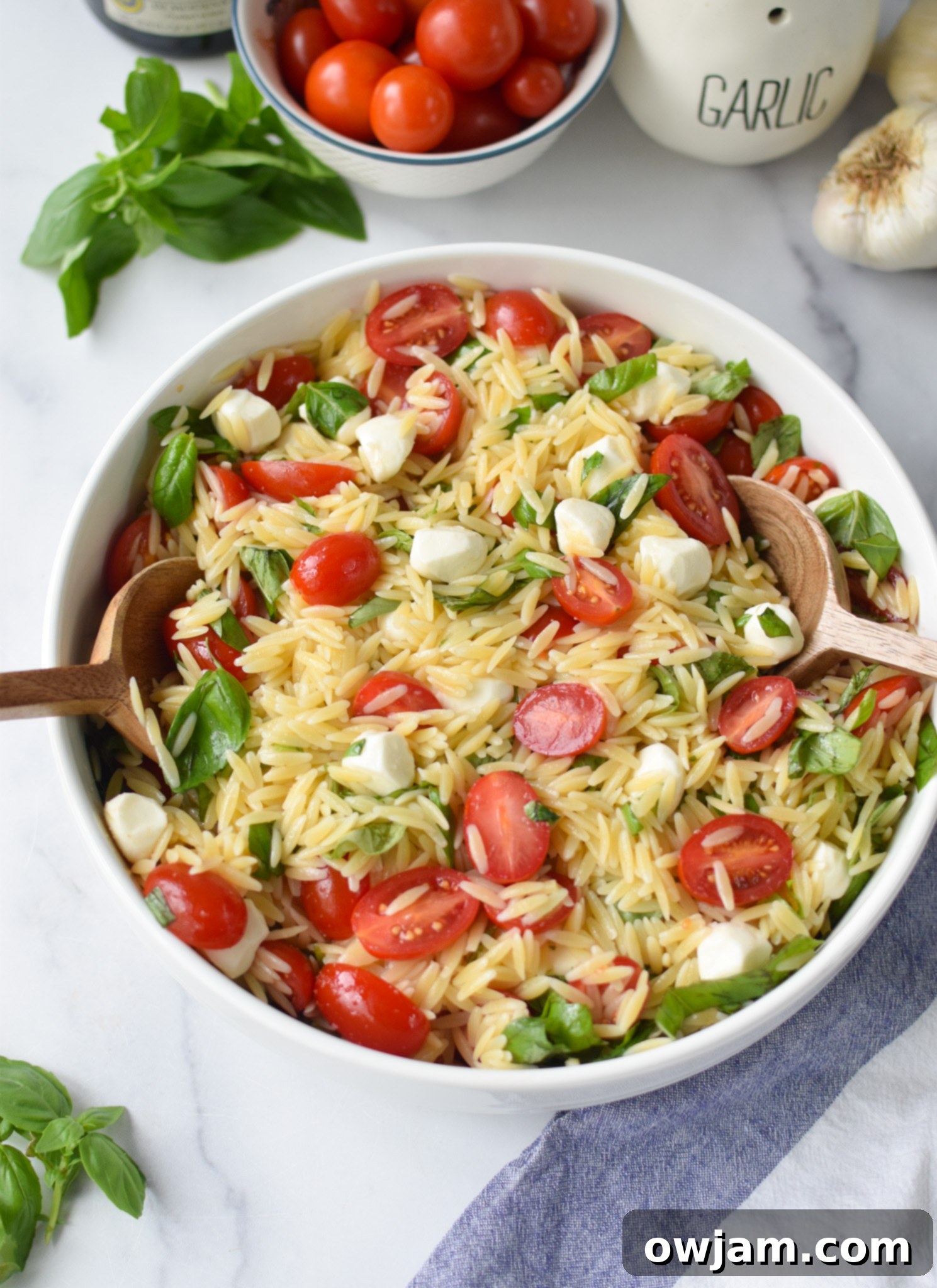 Caprese Orzo Pasta Salad with wooden spoons.