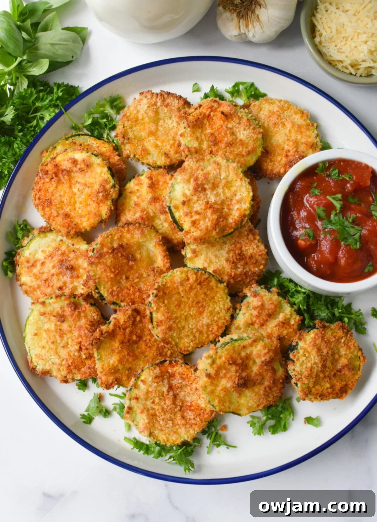 Crispy Air Fryer Zucchini Chips 2 Crispy Air Fryer Zucchini Chips arranged neatly on a white plate, garnished with fresh herbs and ready to be served.