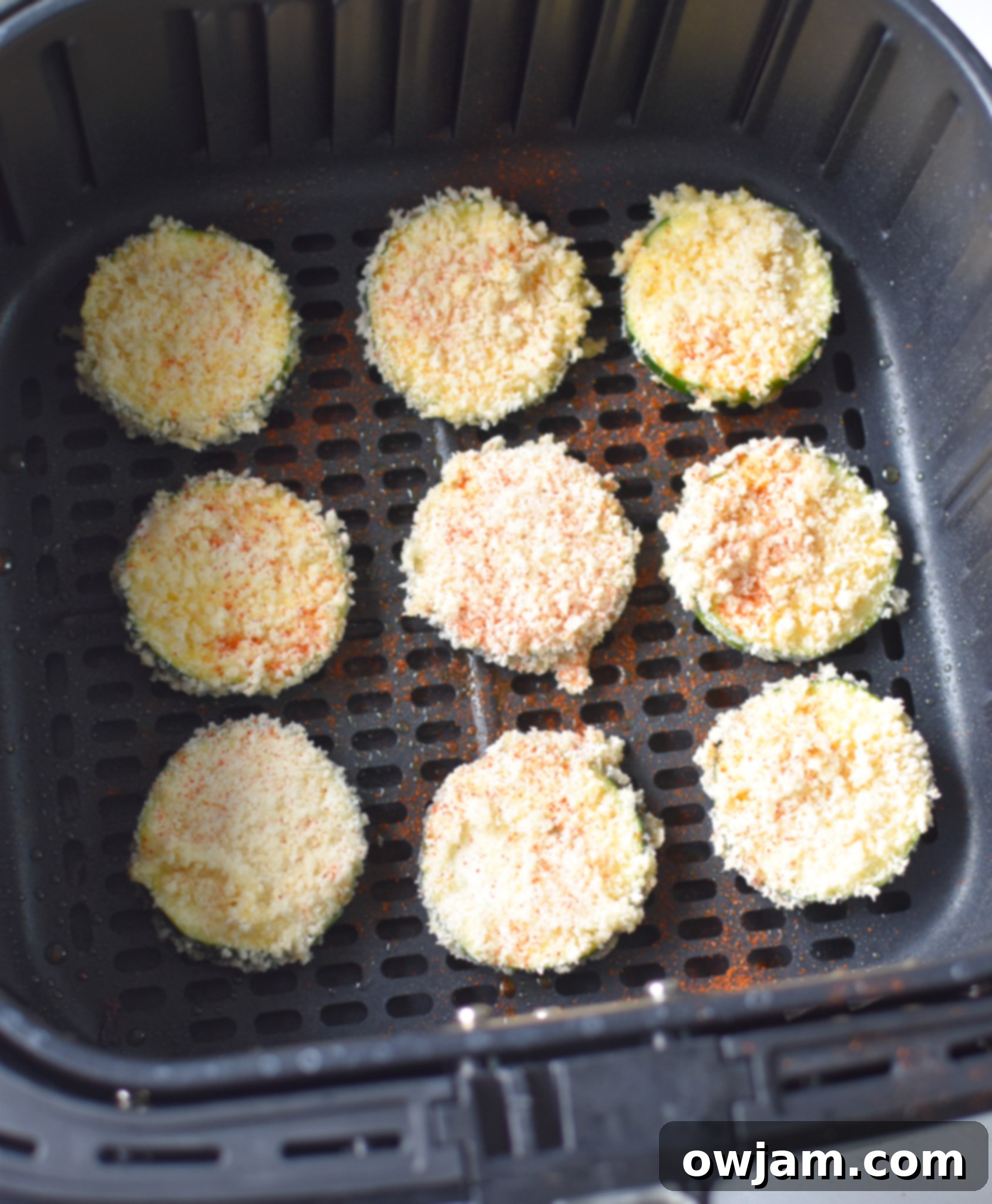 Air Fryer Zucchini Chips cooking in an air fryer basket, showing their golden and crispy texture.