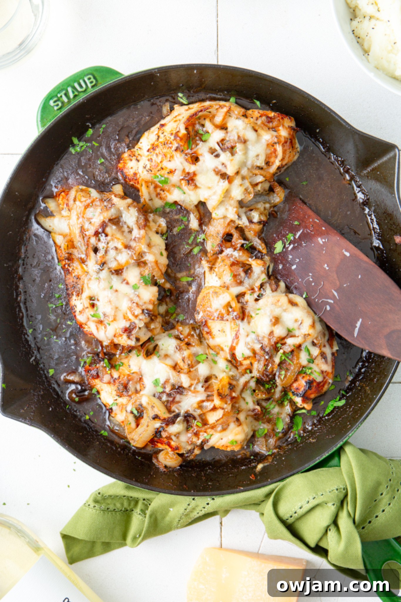 Irresistible French Onion Chicken 9 French Onion Chicken being served from a skillet with a wooden spatula.