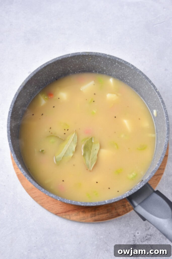 Potato Leek Soup in a pot with bay leaves.