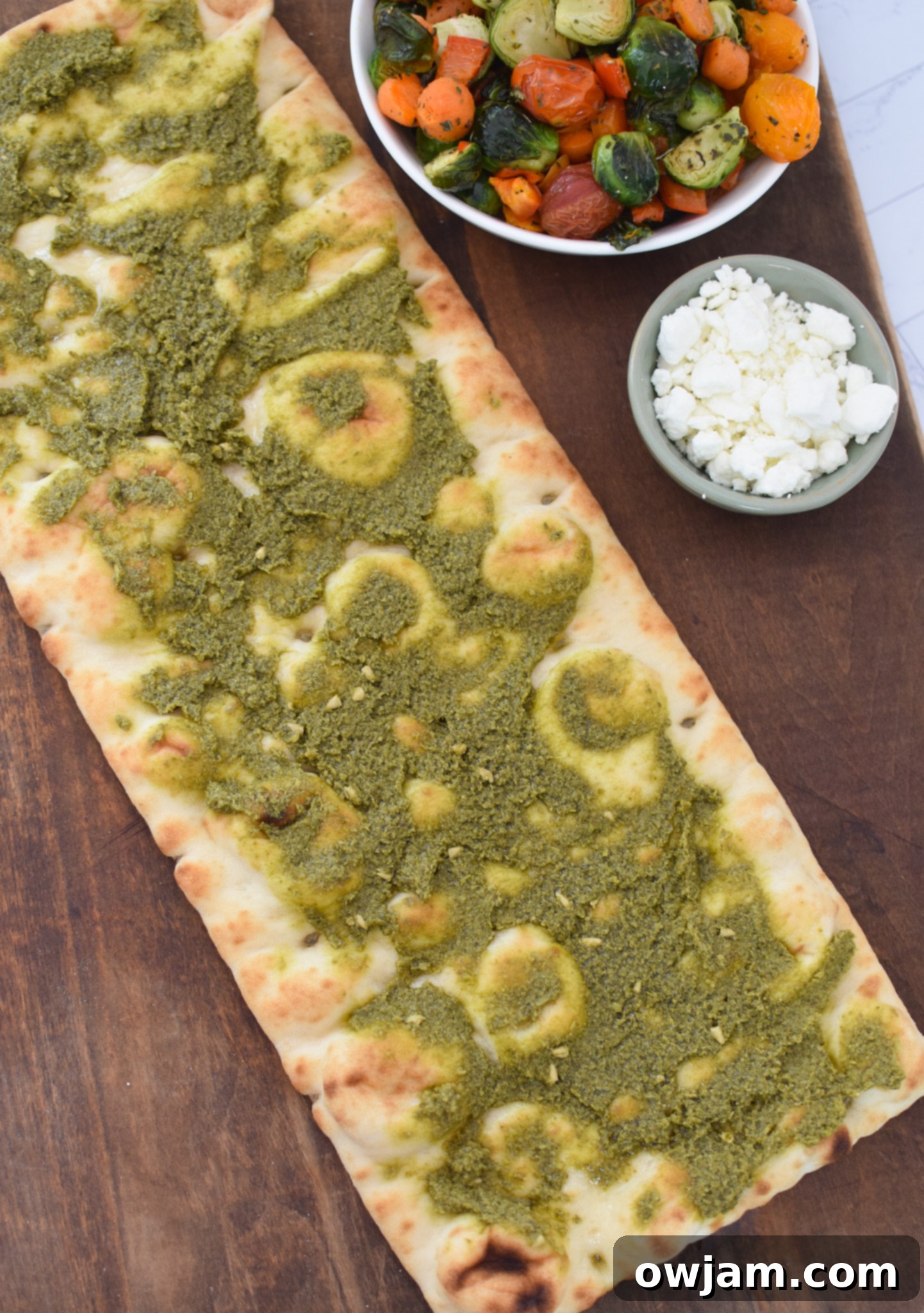 Roasted Vegetable Goat Cheese Flatbread Pizza Recipe with pesto spread on the flatbread.