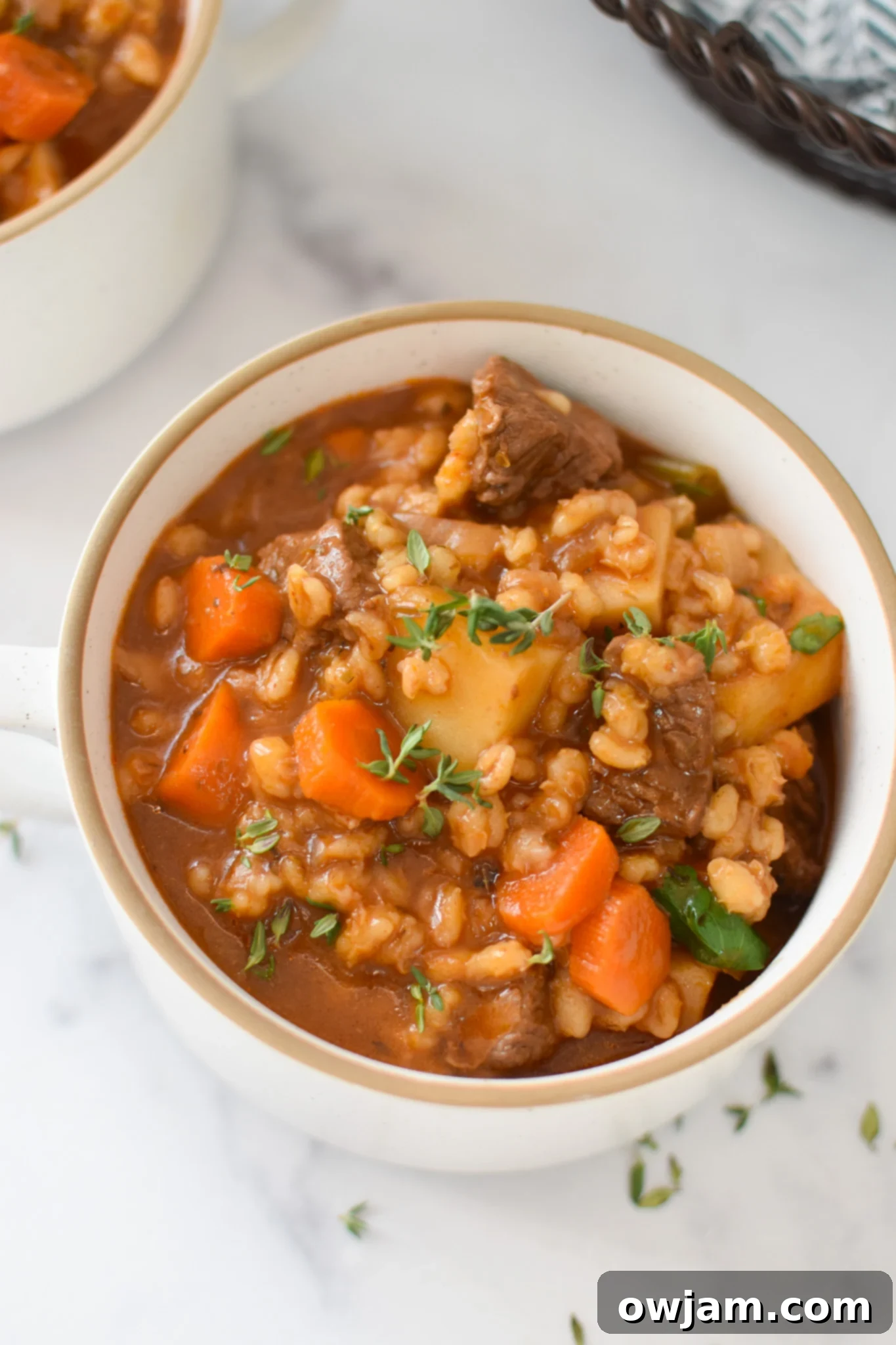 Hearty Slow Cooker Beef Barley Soup 2 Slow Cooker Beef Barley Soup in a white bowl, garnished with fresh herbs.