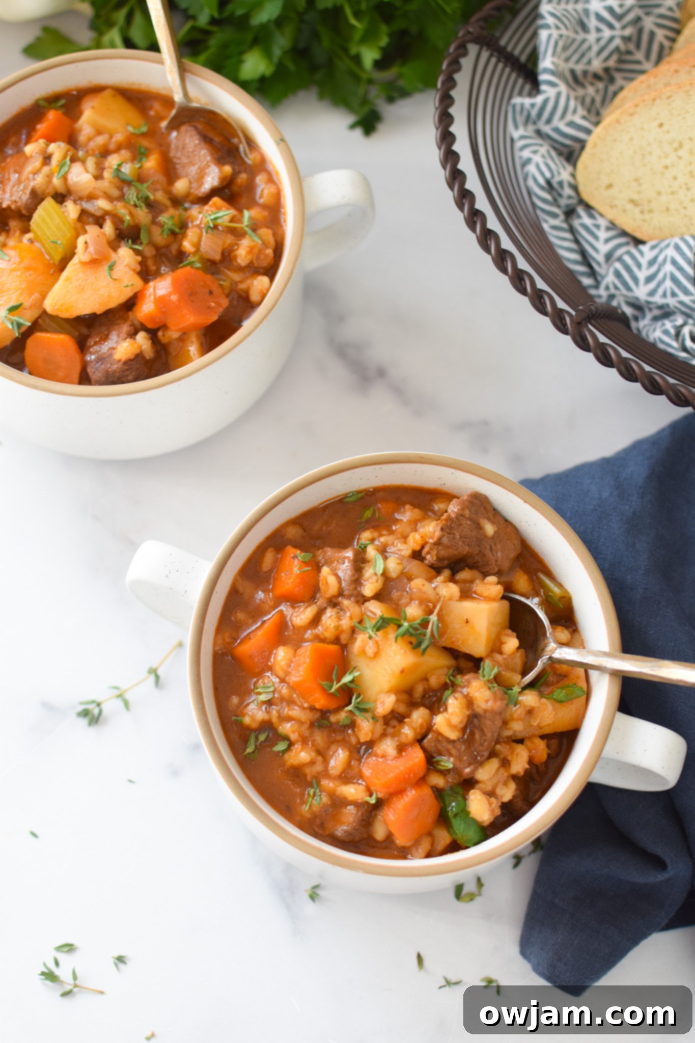 A serving of Slow Cooker Beef Barley Soup in a bowl with a spoon, garnished with fresh herbs.