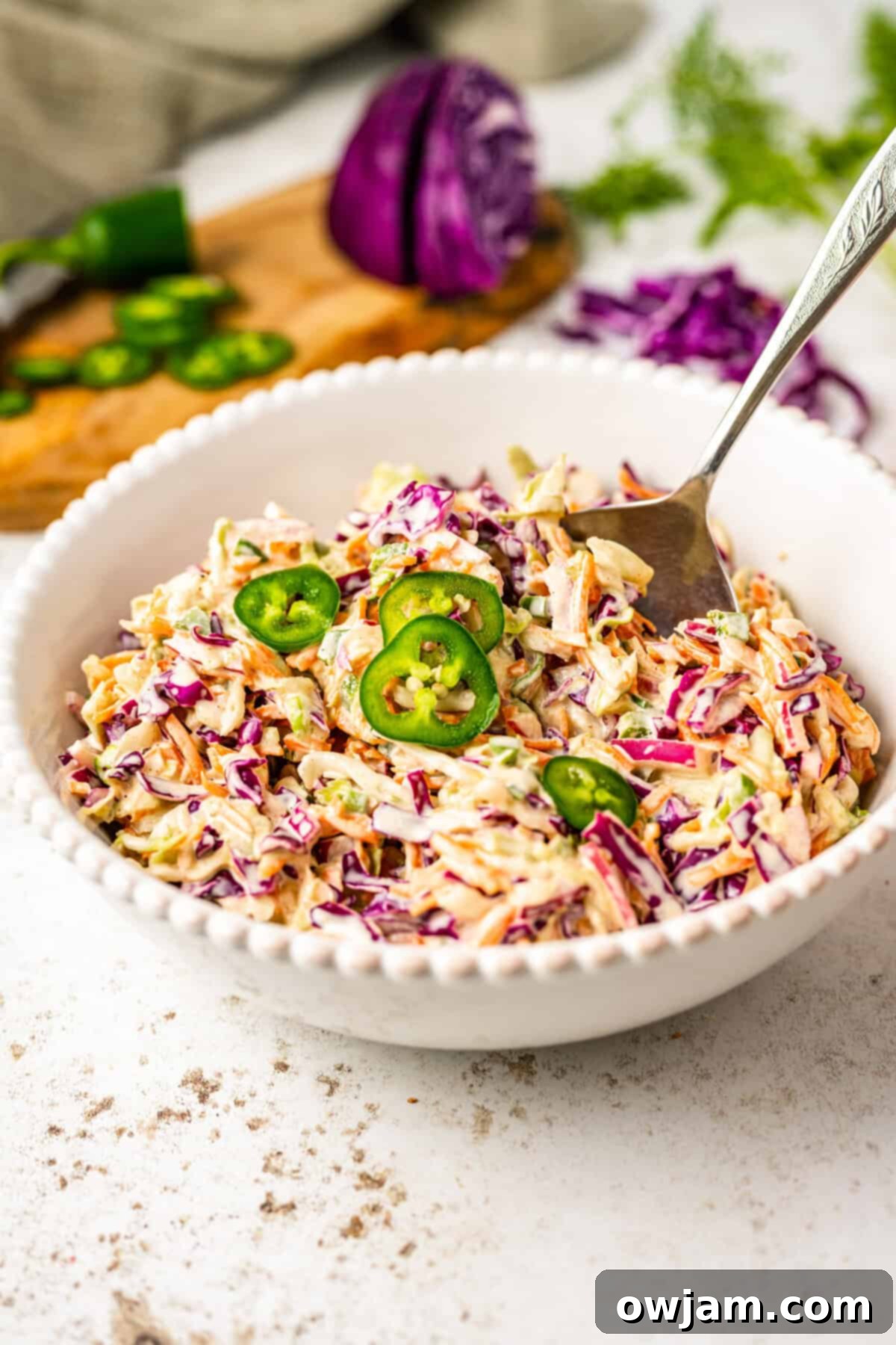 Spicy Jalapeno Coleslaw 2 Jalapeño Coleslaw Recipe in a white bowl with a fork, ready to be served.