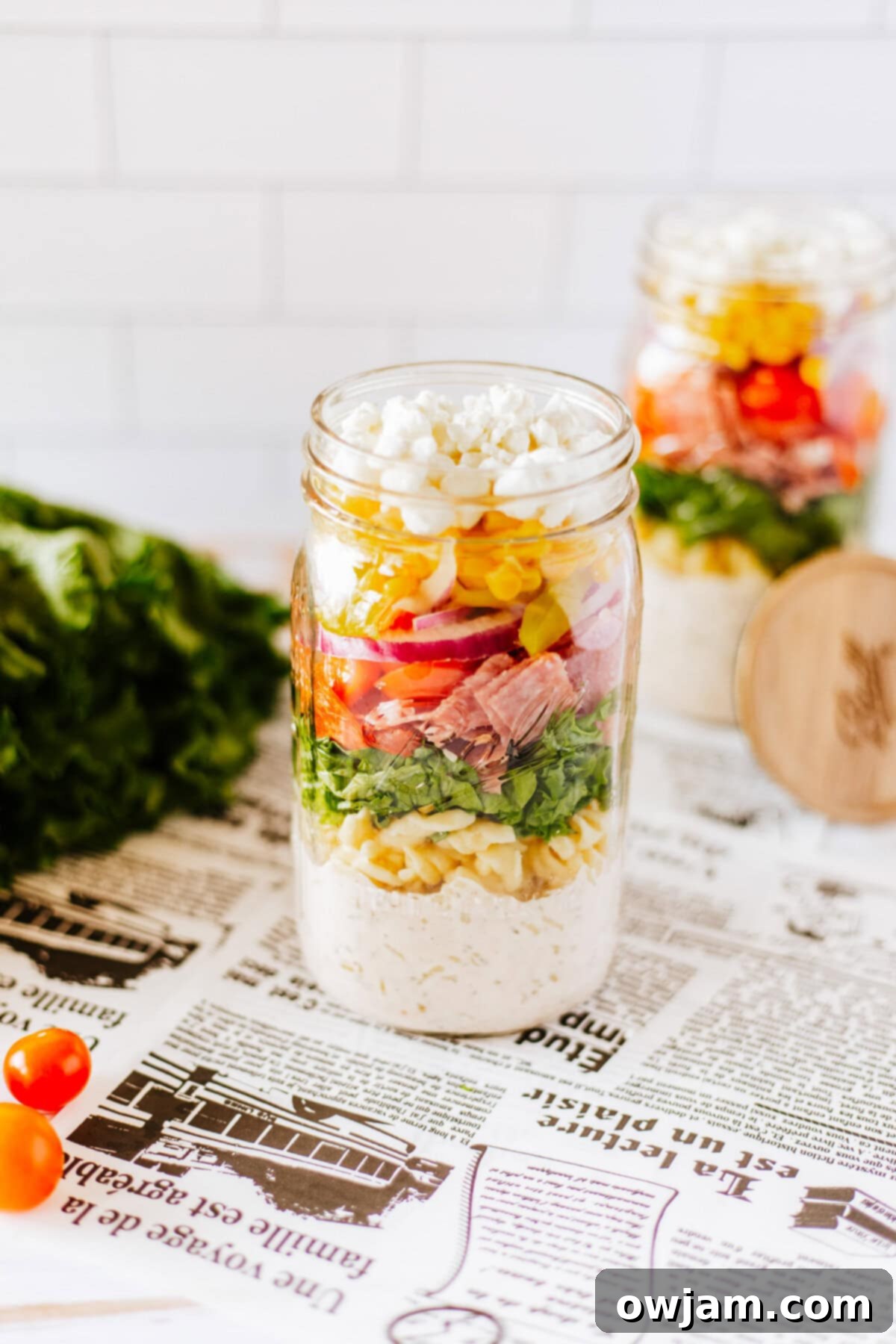 Two Italian Pasta Mason Jar Salads in clear glass jars, neatly lined up.