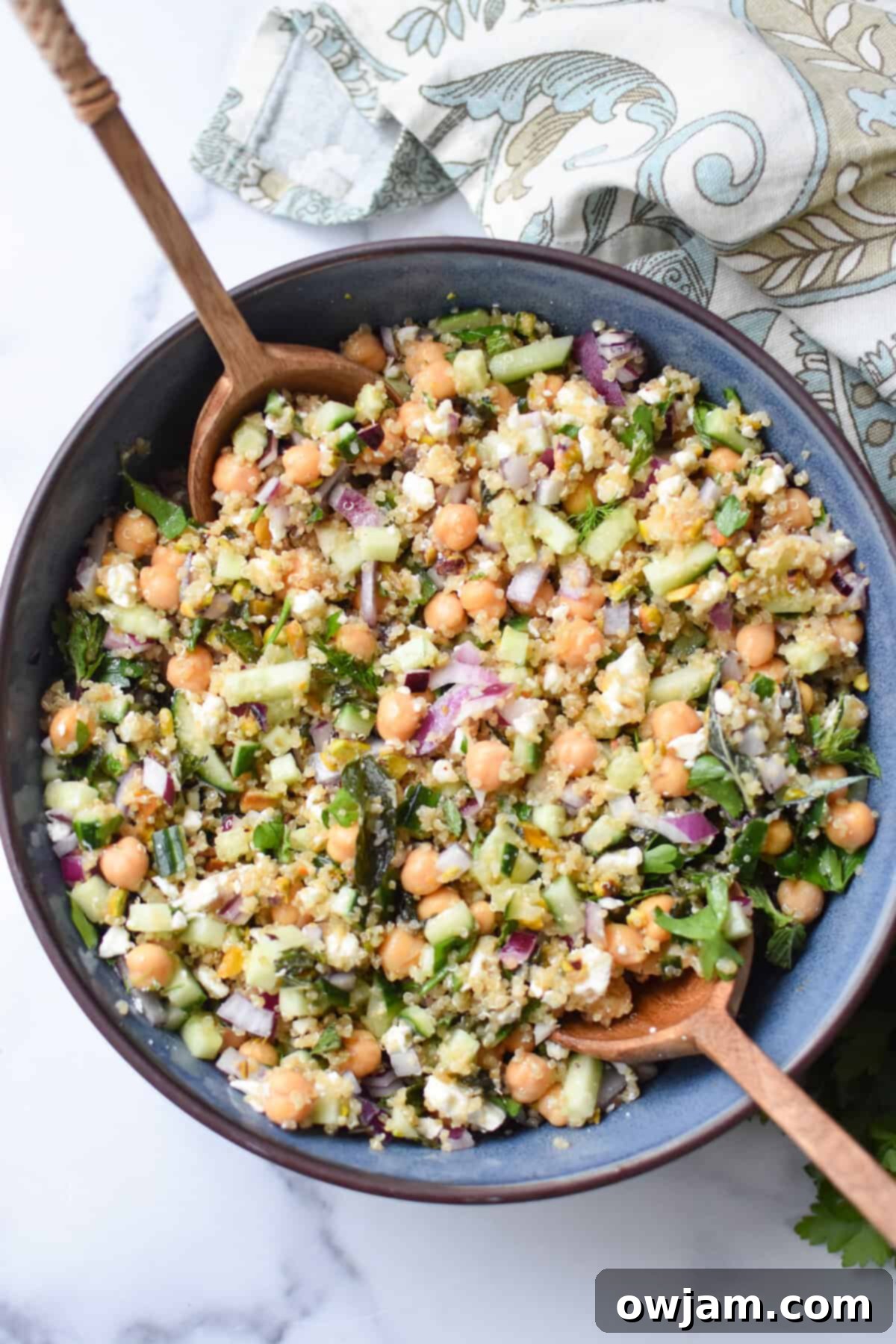 an overhead shot of a Jennifer Aniston salad in a blue salad bowls with wooden spoons on each side. 