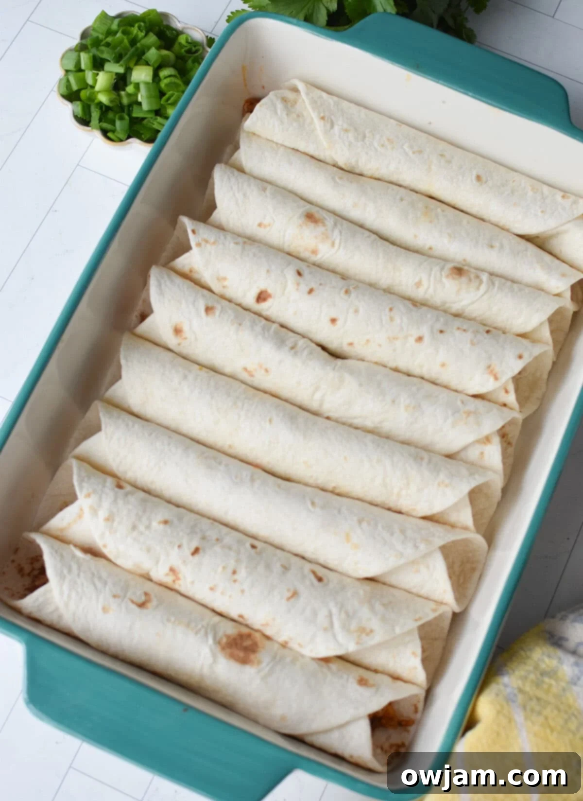 Simple Pork Enchiladas in Minutes 5 Rolled tortillas filled with pork and cheese, neatly arranged seam side down in a casserole dish, ready for sauce and baking.