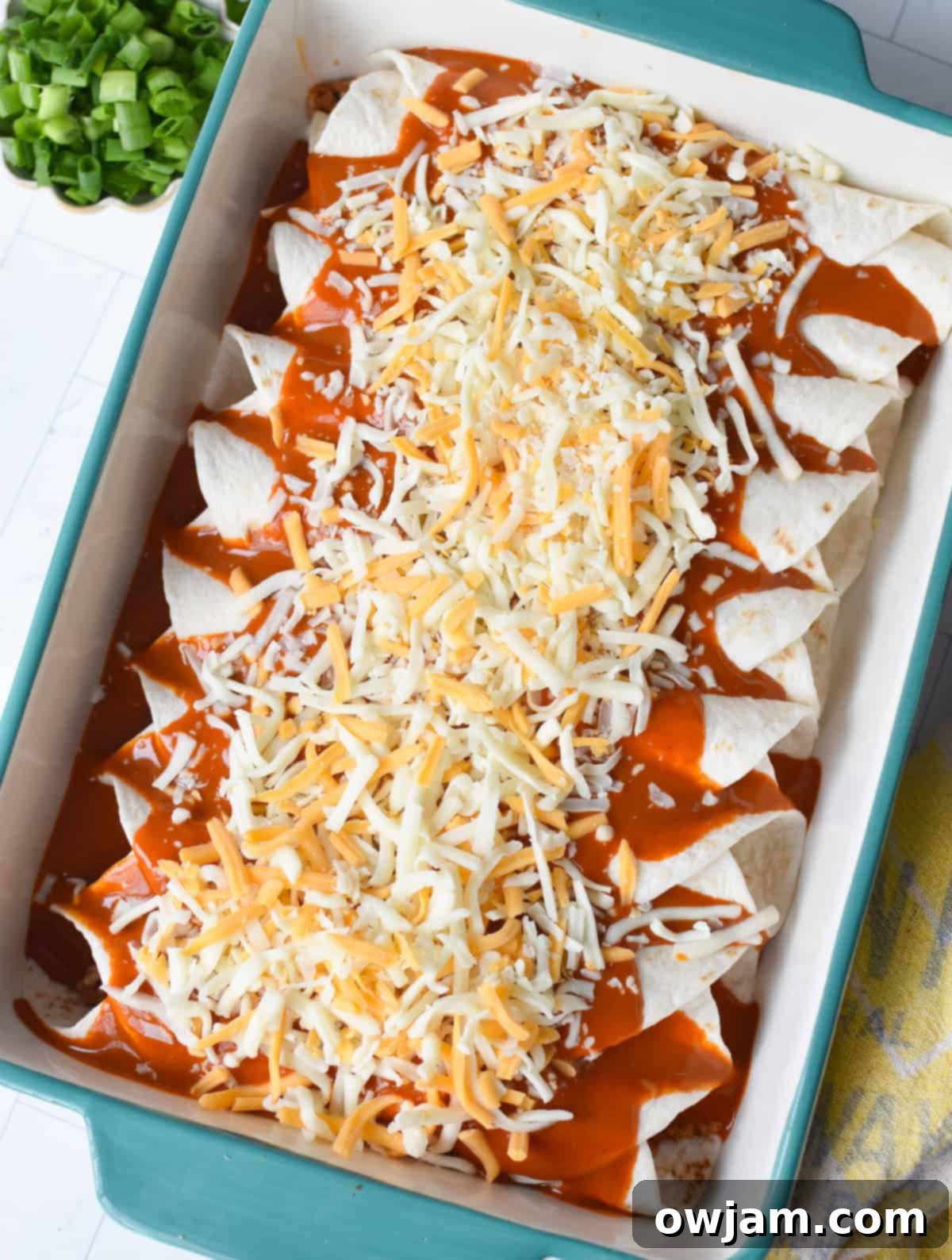 Simple Pork Enchiladas in Minutes 6 Rolled enchiladas in a baking dish, generously covered with red enchilada sauce and a medley of shredded cheeses, ready for baking.