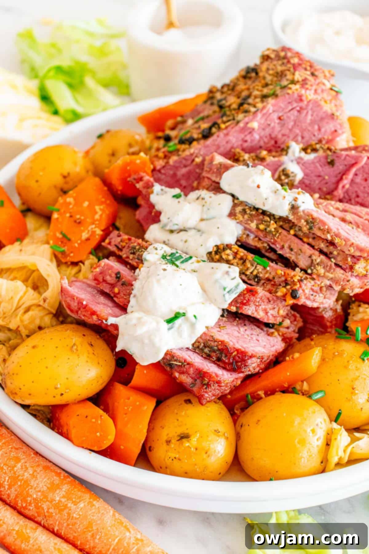 Homestyle Baked Corned Beef & Cabbage 5 Sliced Baked Corned Beef and Cabbage on a plate, topped with creamy horseradish sauce