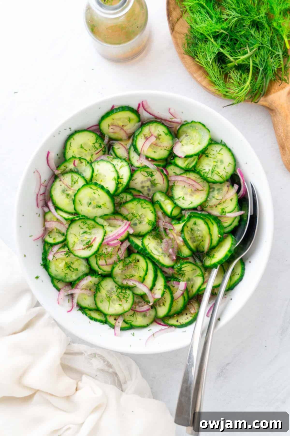 Fresh Cucumber Onion Salad served in a bowl with two serving spoons