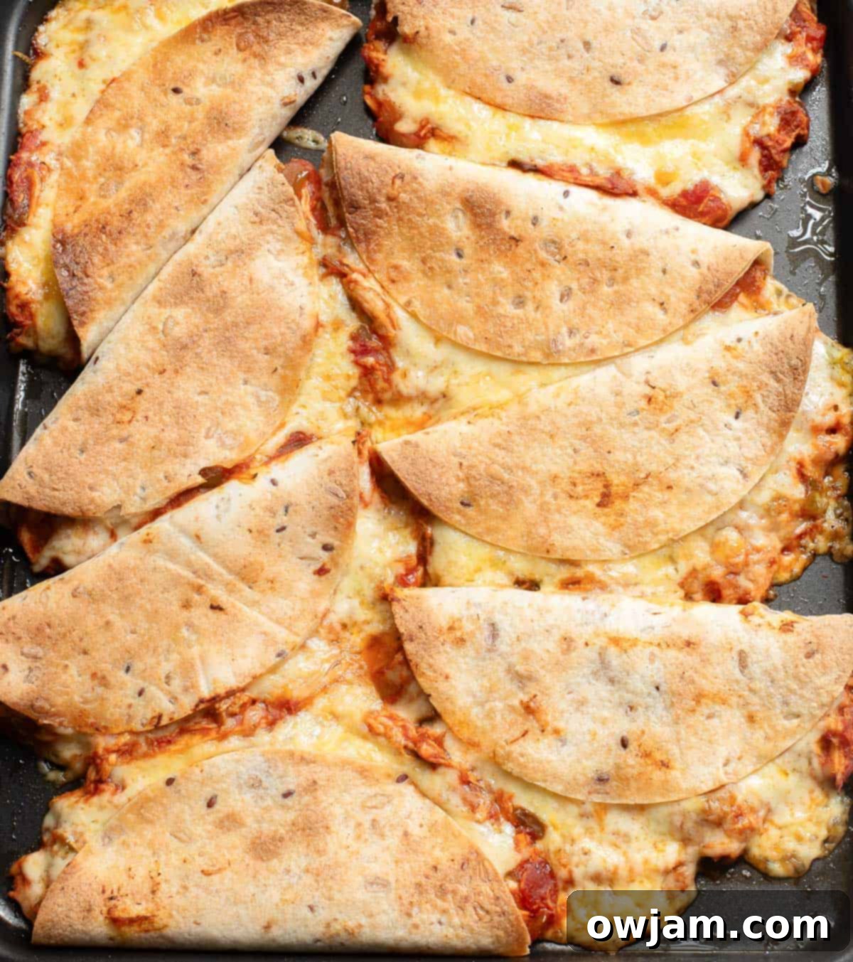 Several baked chicken tacos neatly arranged on a tray, ready to be served