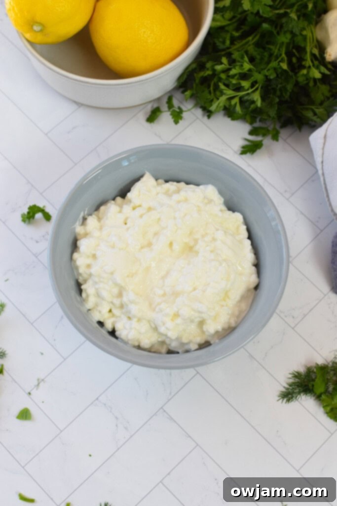 Velvety Cottage Cheese 4 Ingredients laid out for making whipped cottage cheese, including cottage cheese, fresh herbs, and lemon