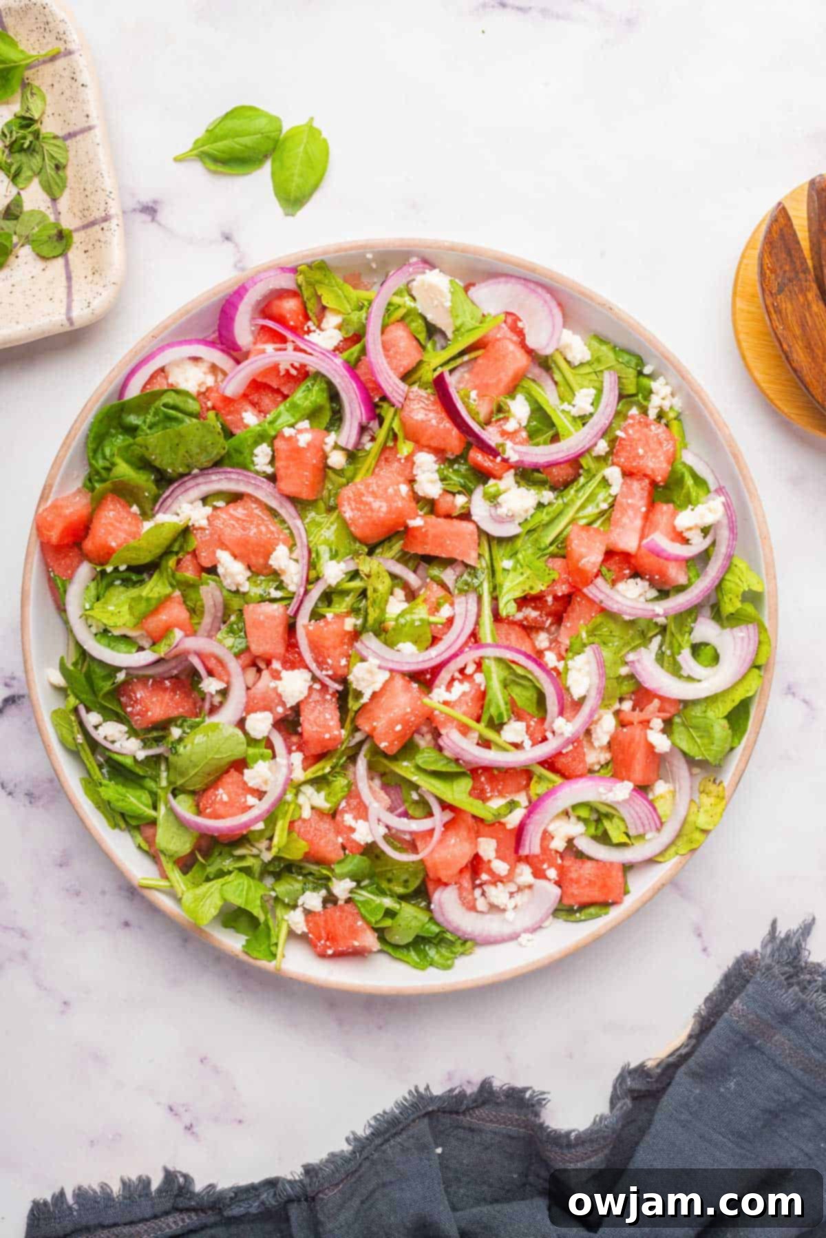 Vibrant Watermelon Arugula Salad artfully arranged on a white plate, highlighting fresh ingredients.