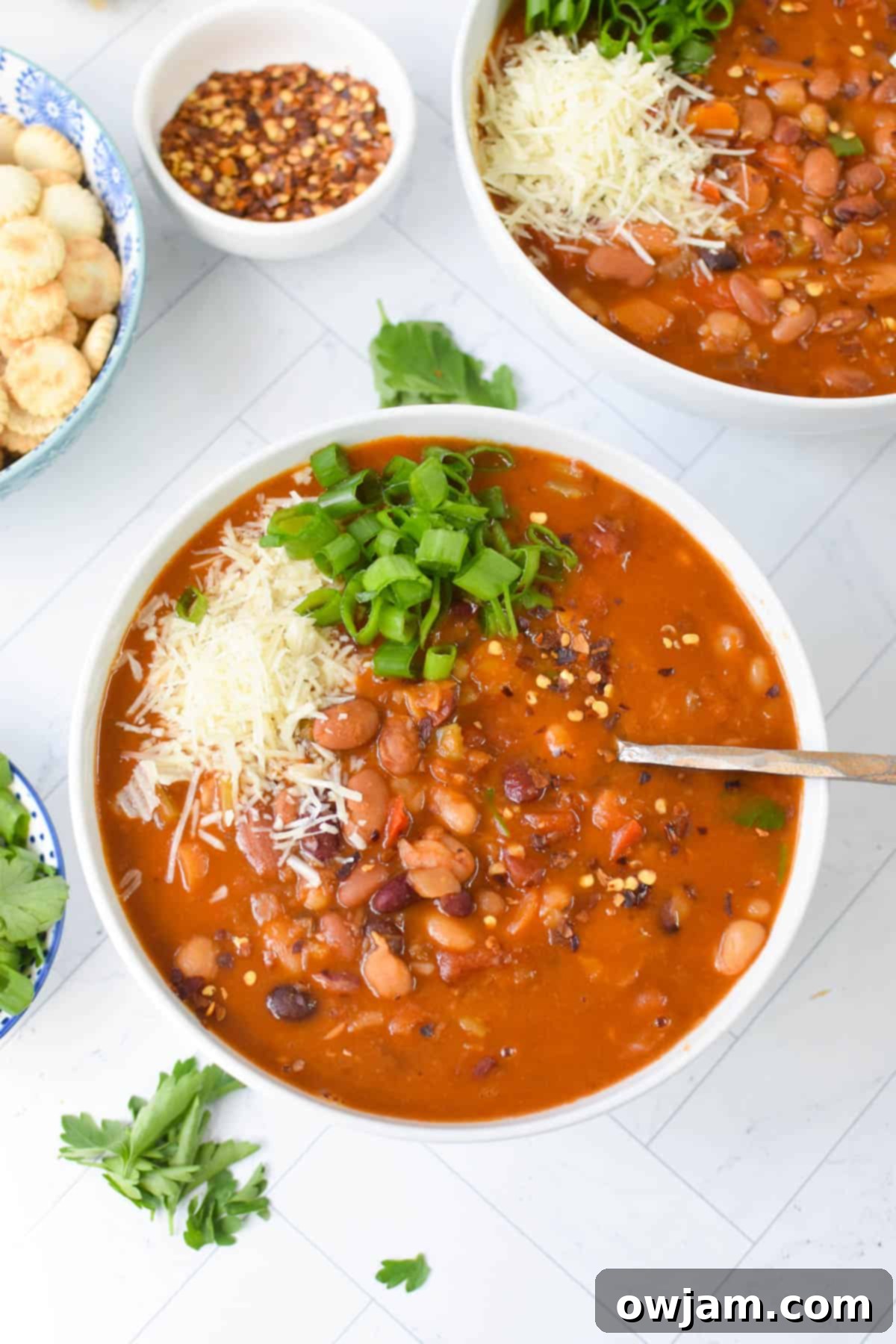 A serving of Instant Pot 15 Bean Soup topped with cheese and herbs.